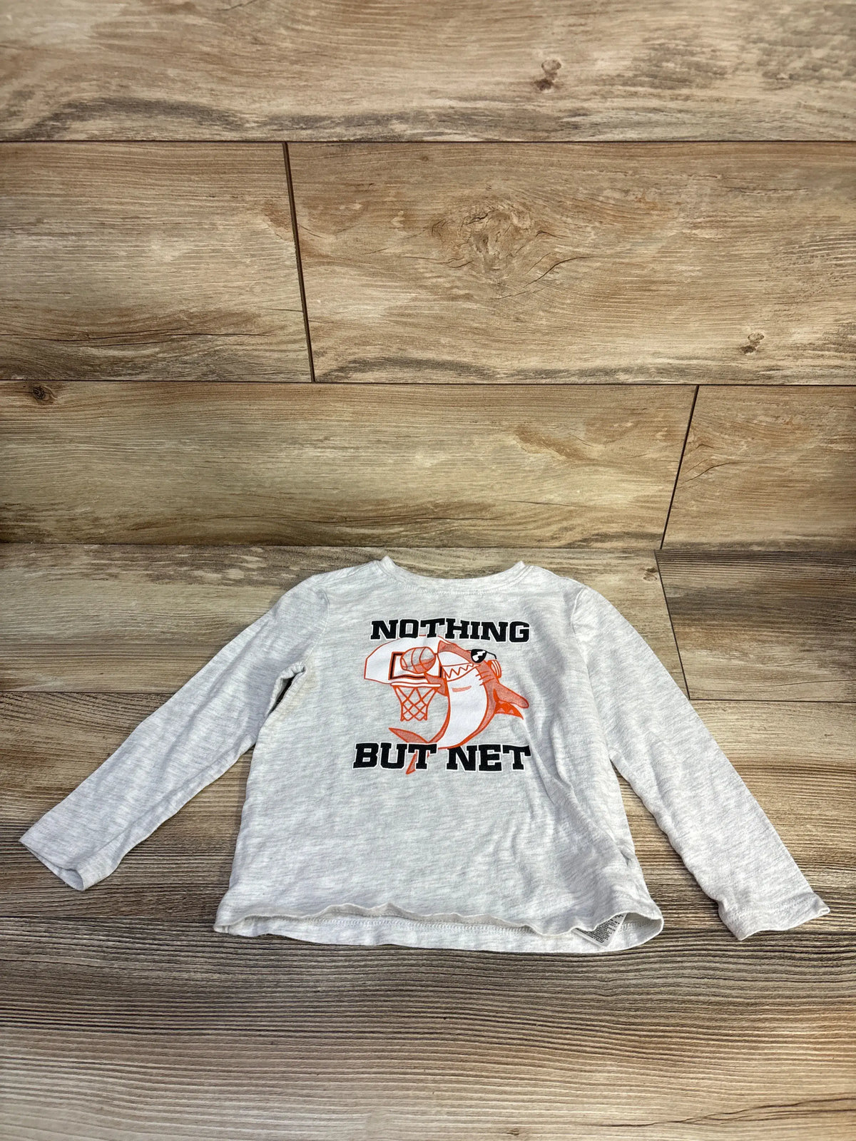 Front view of Old Navy Nothing But Net shirt showcasing gray long sleeves and basketball graphic on wood floor