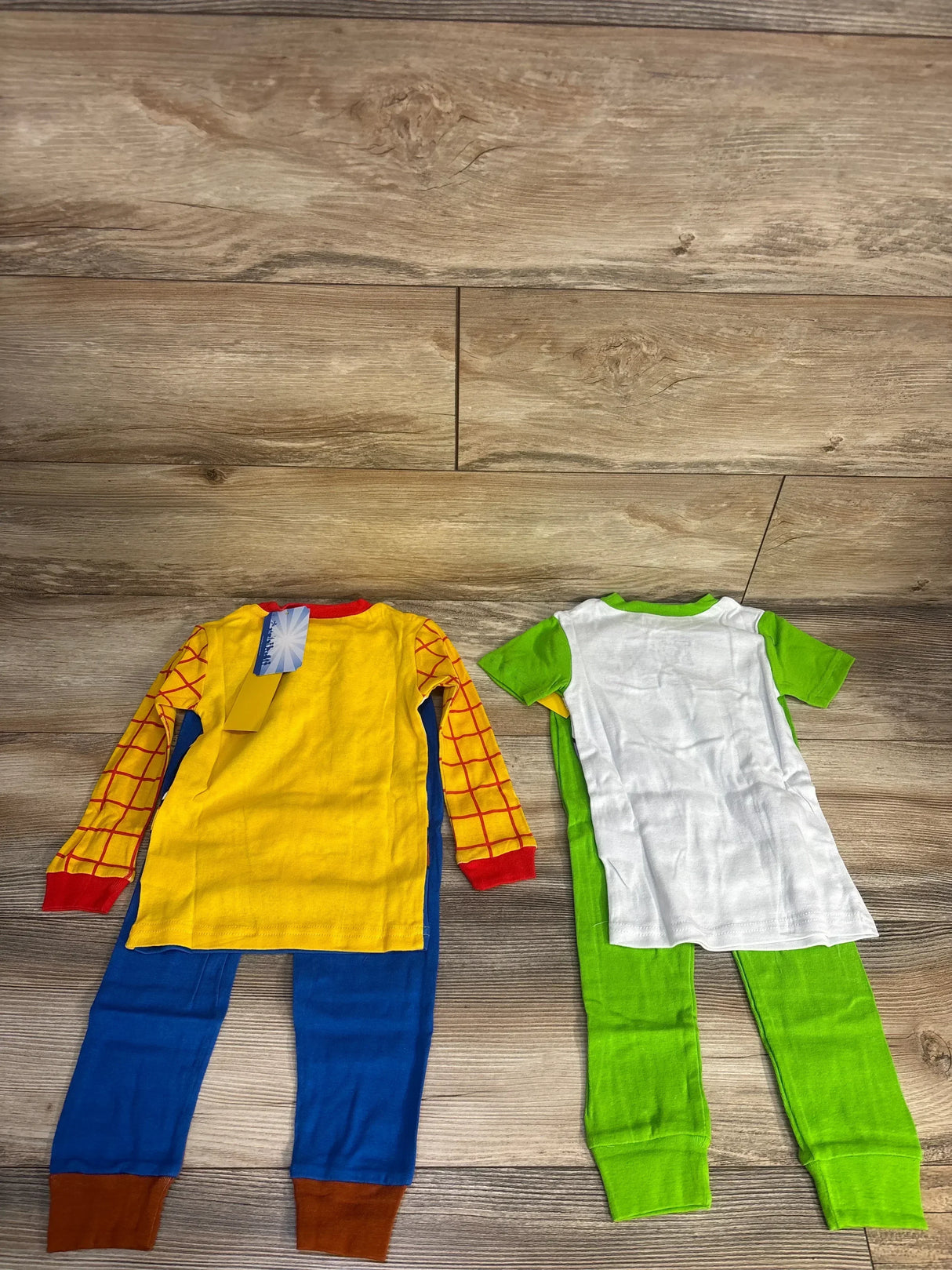 Kids cartoon pajamas with yellow, red, blue, and green sets on wood floor