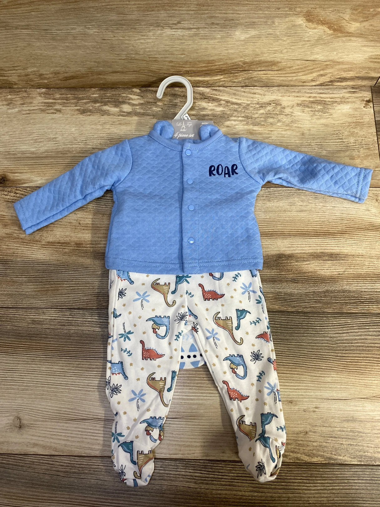 Blue baby jacket with 'ROAR' text and dinosaur print pants set on wood background