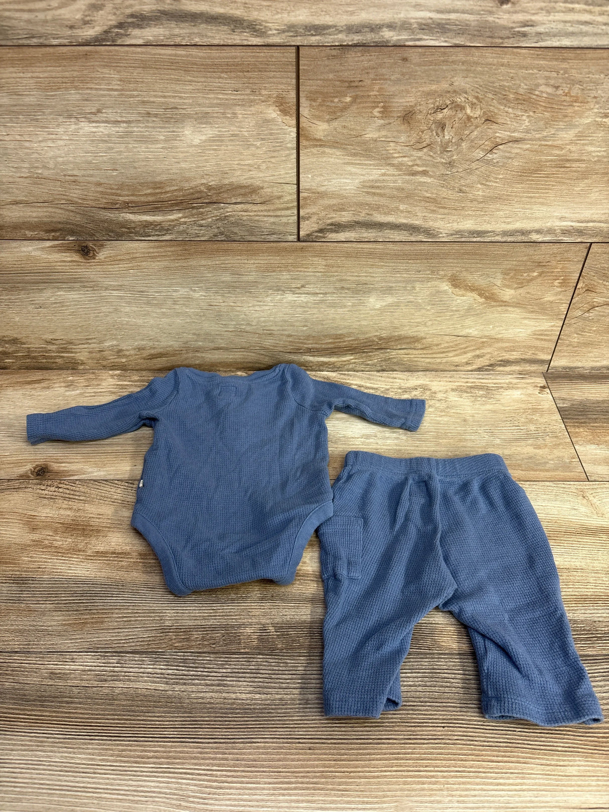 Blue long sleeve baby bodysuit and pants set on wood floor, kids clothing resale