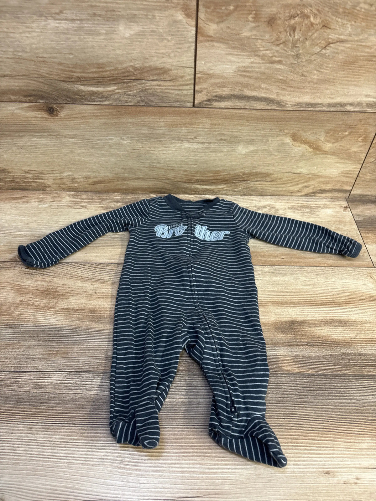 Flat lay of Carter’s navy striped footed sleeper showing Brother embroidery, front zipper and feet on wood background