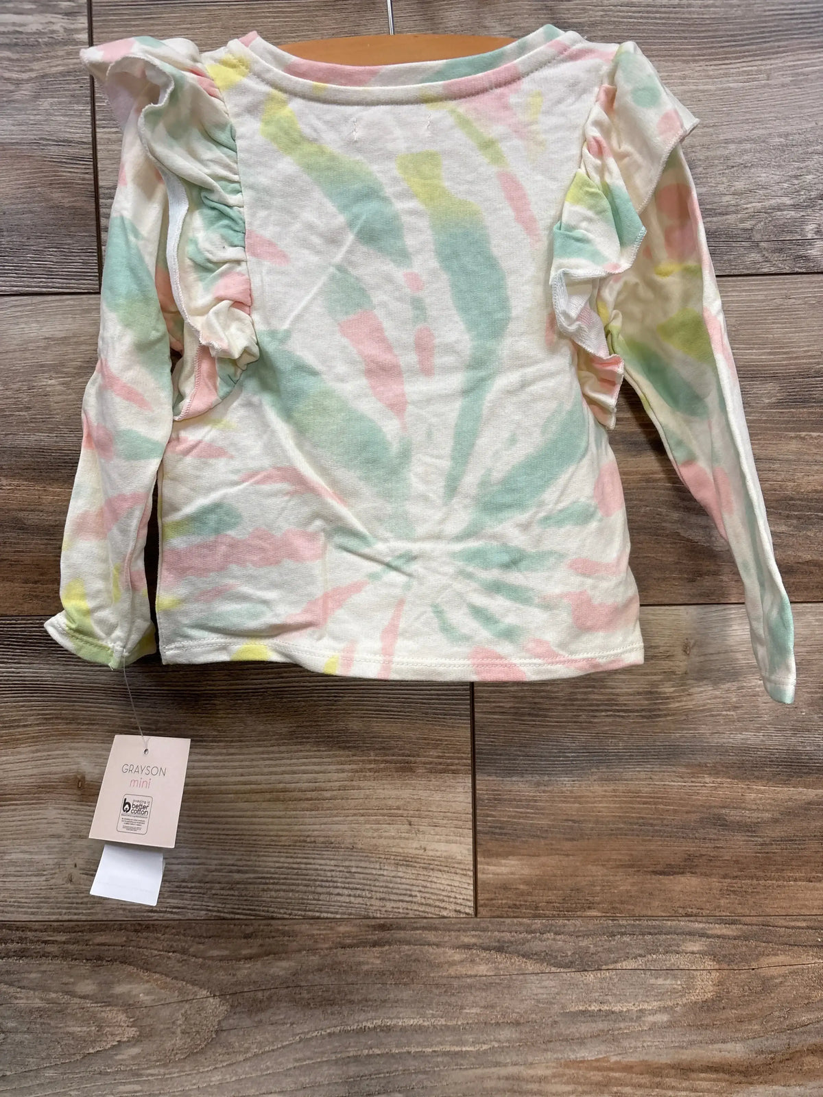 Grayson Mini girl's long sleeve tie-dye shirt with ruffle details on sleeves on wooden floor