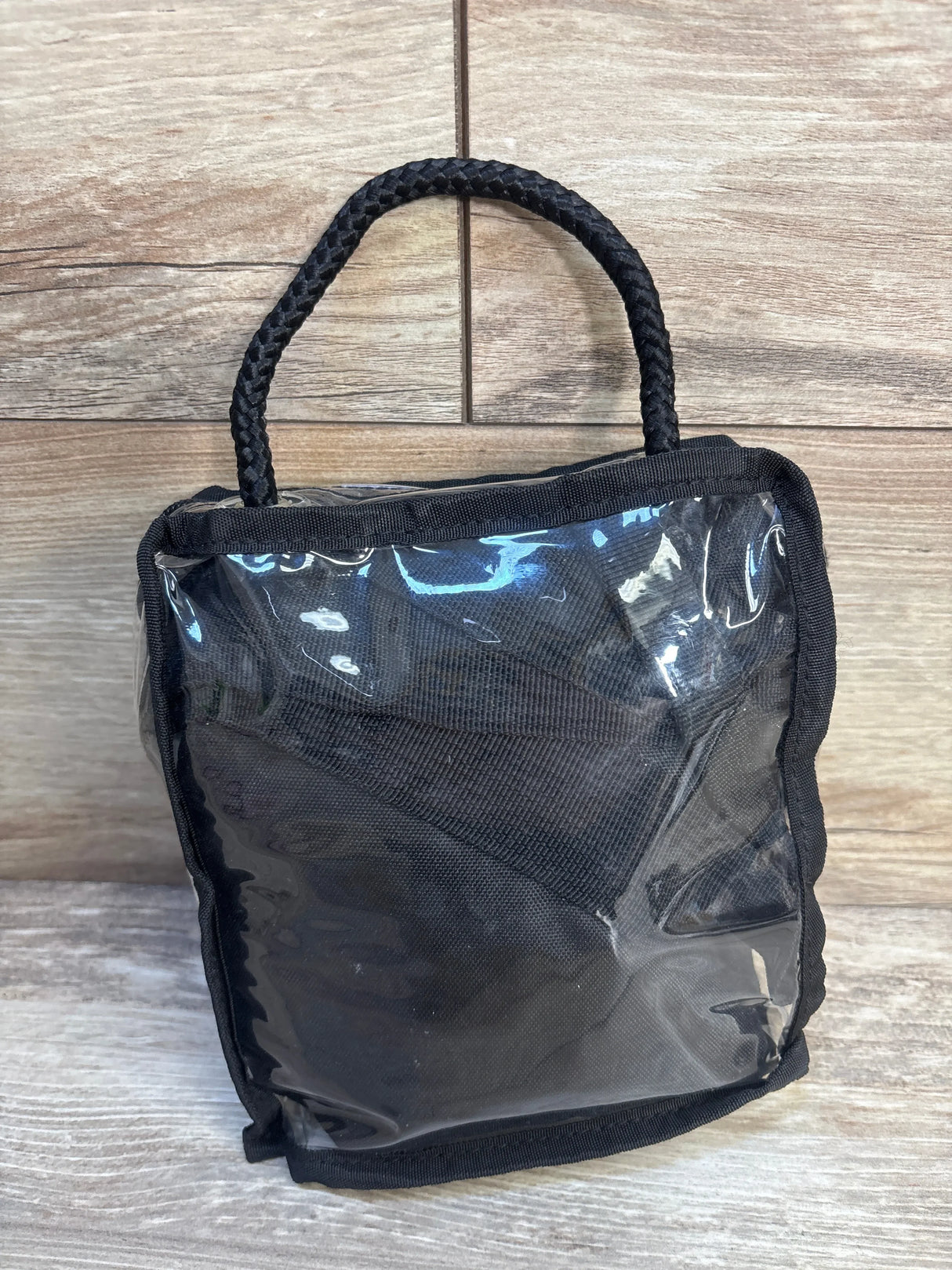 Front view of Twin Z Pillow Twin Feeding Pillow travel bag showcasing clear vinyl front panel and braided handle on wood floor background