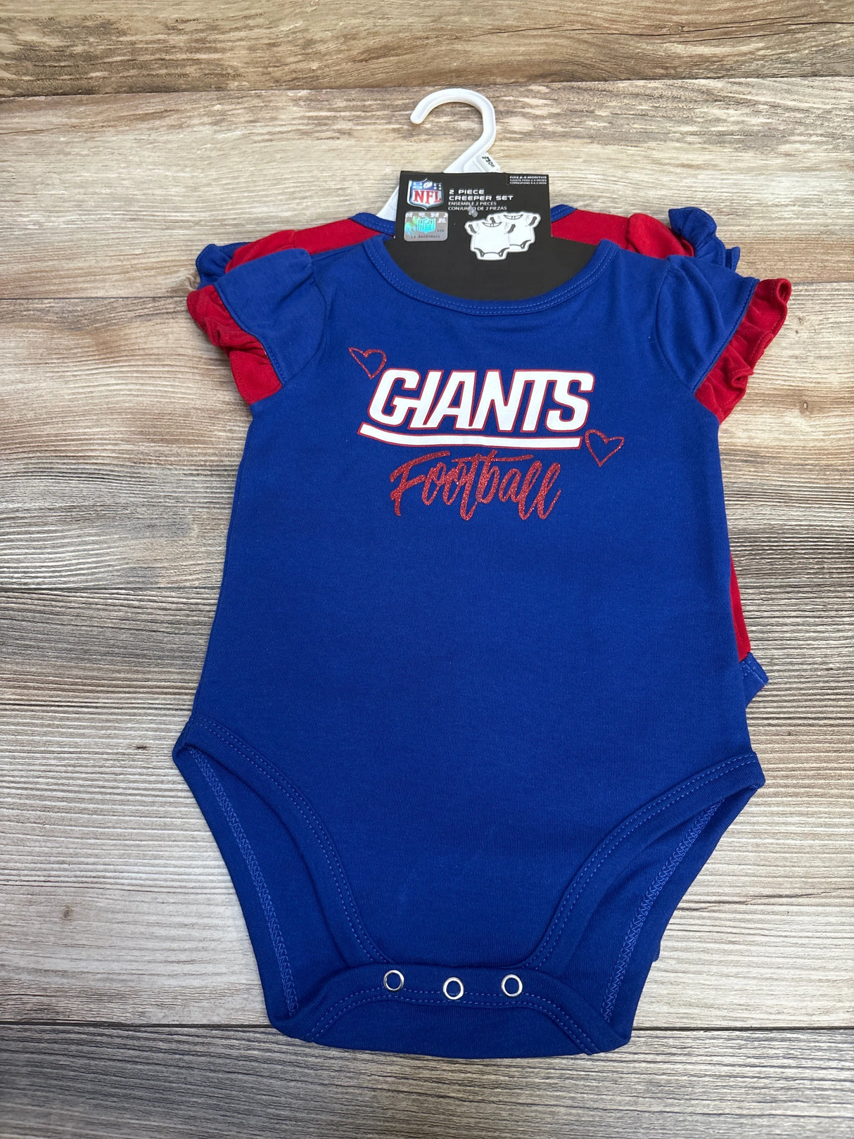 Blue baby onesie with red hearts and Giants Football logo, NFL 2-piece creeper set on wooden background