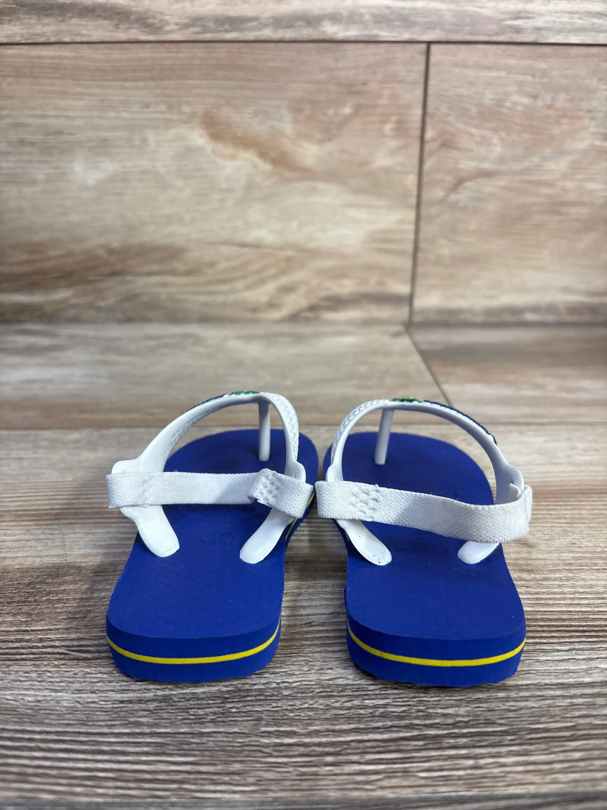 Front view of Havaianas Flip Flops Blue sz 6c showcasing white thong straps and elastic ankle straps on a wood floor
