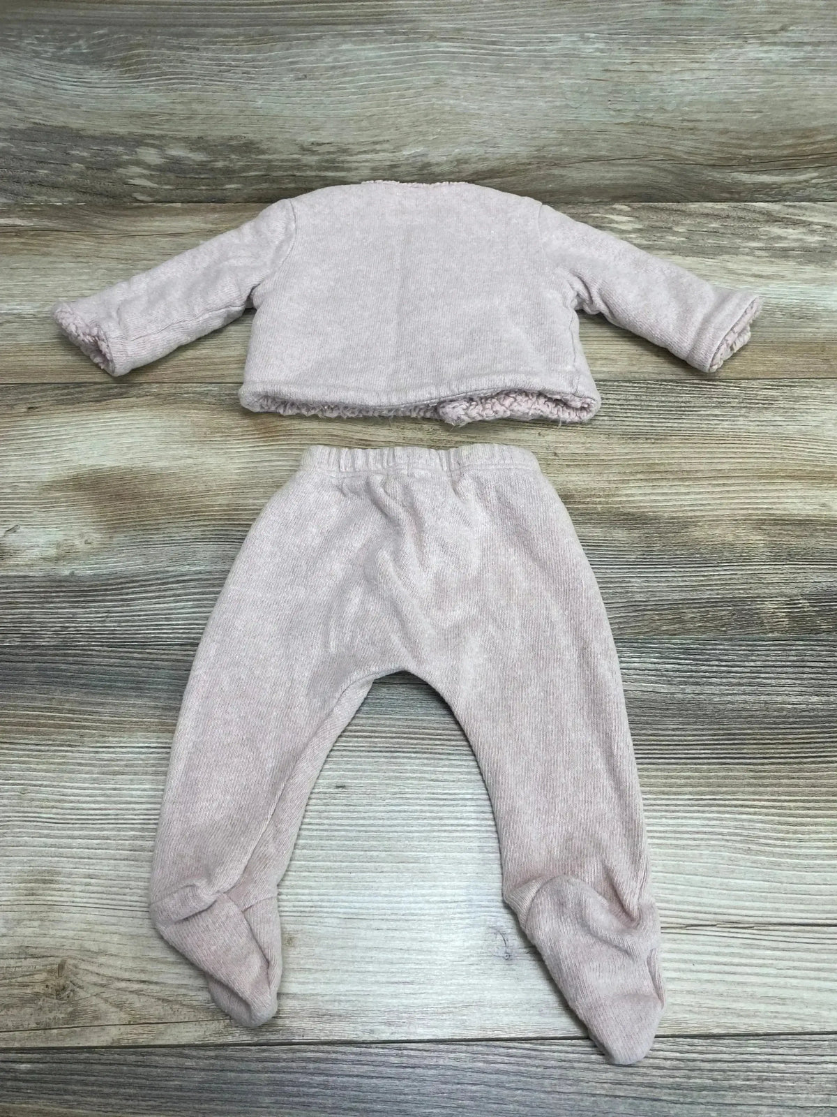 Flat lay of Petit Indi 2-piece organic pink baby set showing sherpa-lined jacket and footed pants on wood background