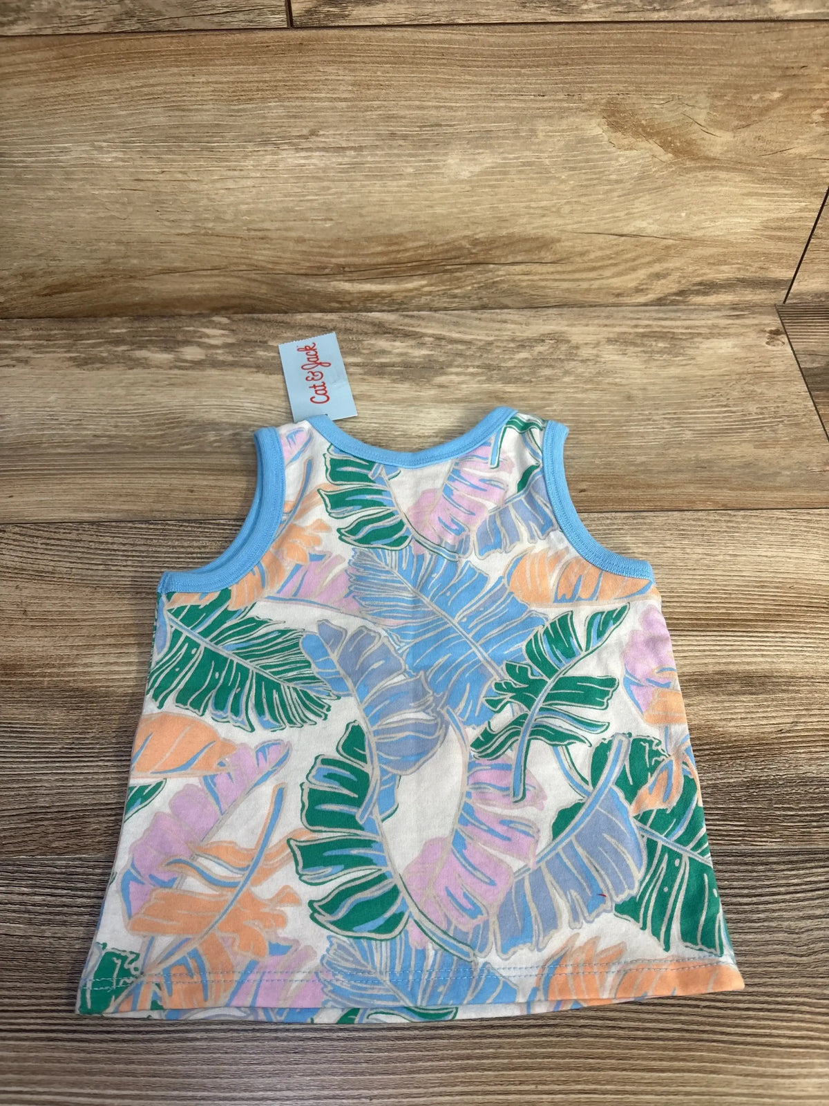 Flat-lay of Cat & Jack toddler floral tank top showcasing pastel tropical leaf print and blue trim on wood background