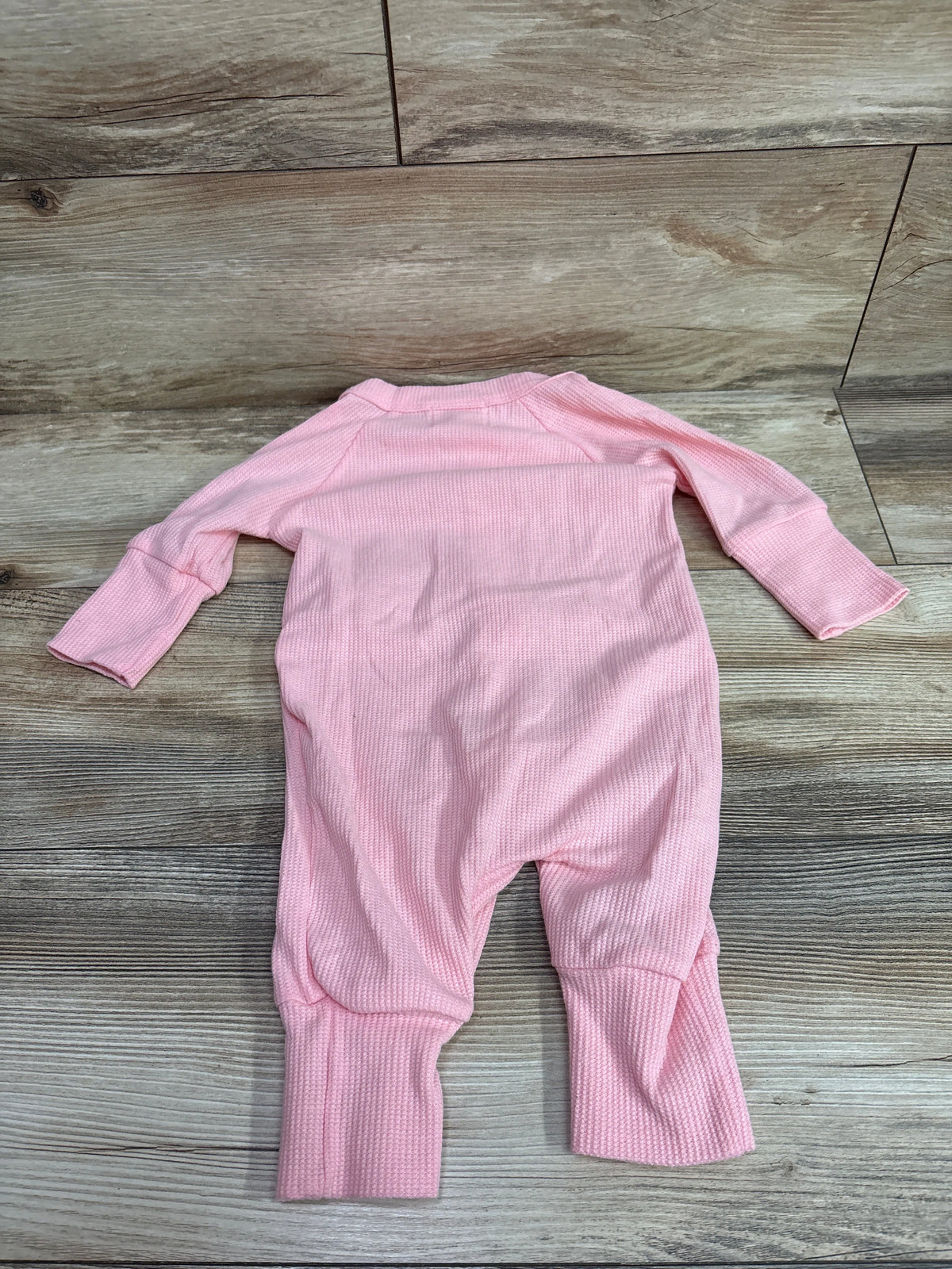 Fable & Ford pink waffle knit baby coverall laid flat on a wooden background