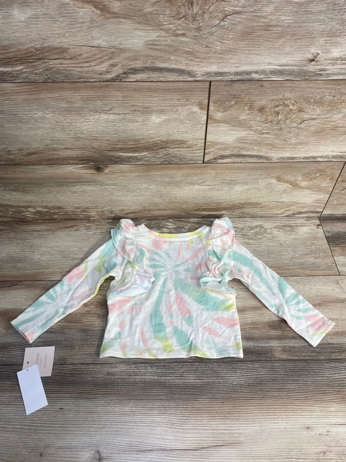 Toddler long sleeve ruffle shirt with pastel tie-dye pattern on wooden floor