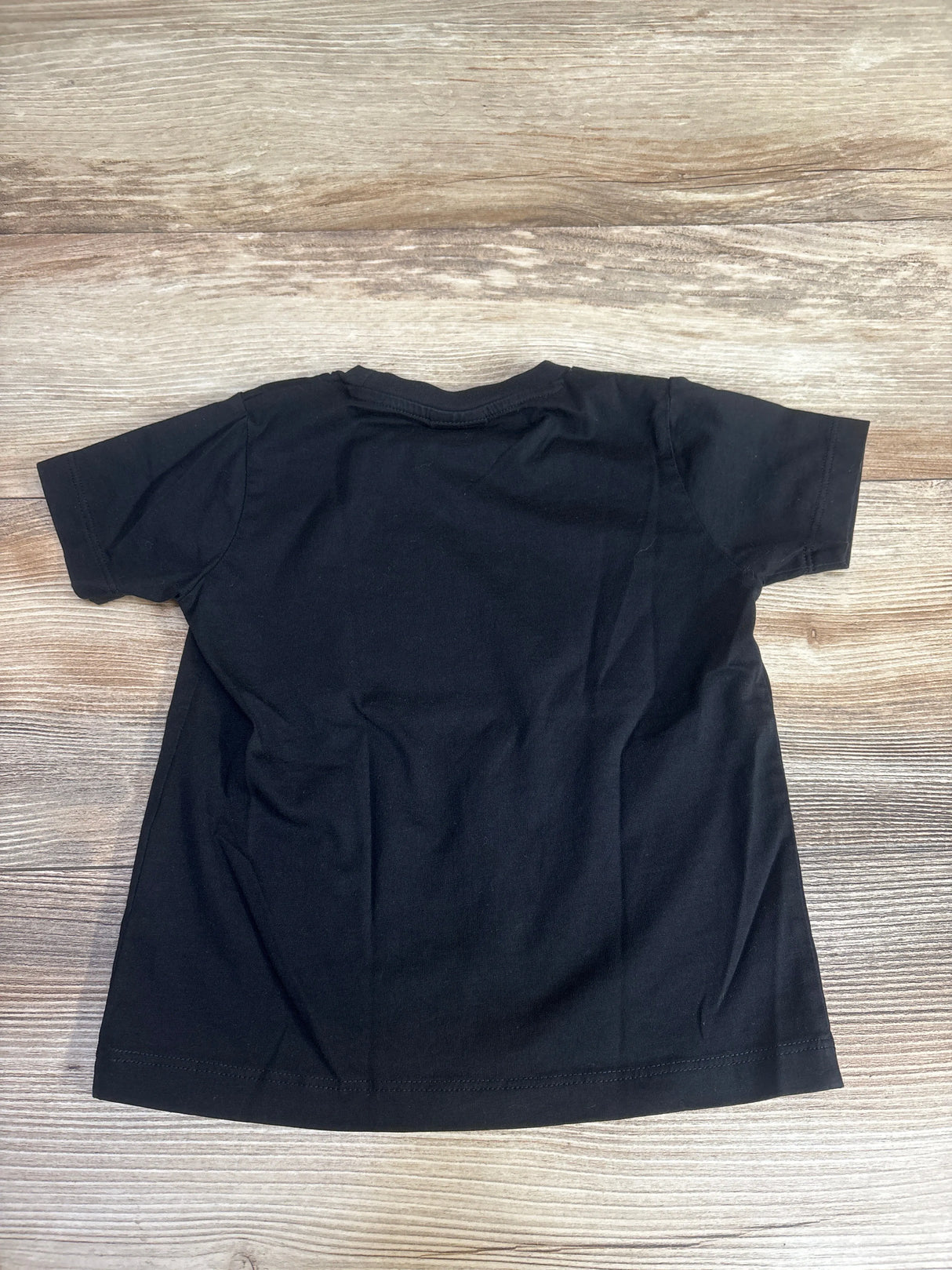 Plain black t-shirt back view on wood background, short sleeve cotton shirt