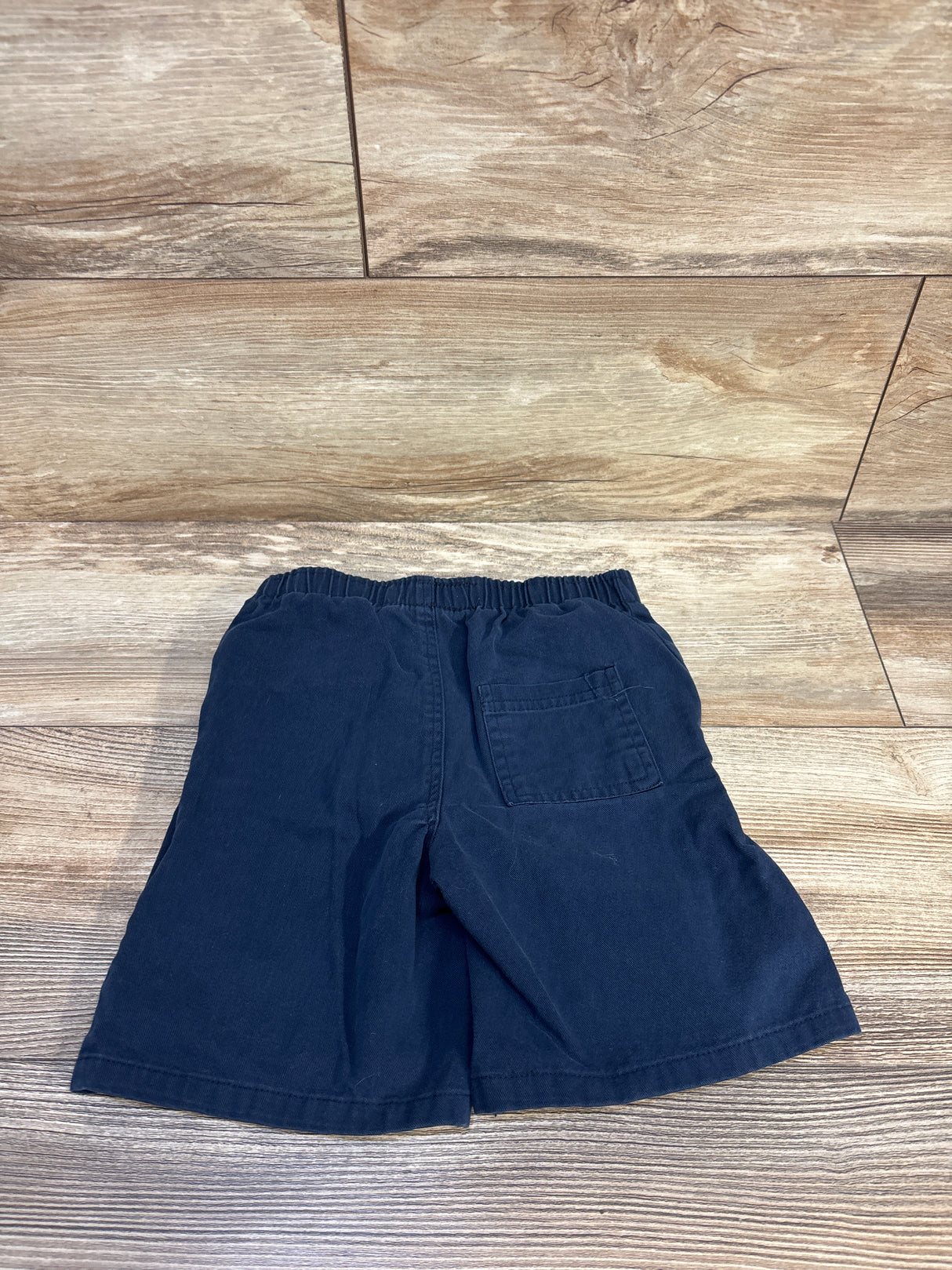 Navy blue kids shorts with elastic waist and back pocket on wooden floor