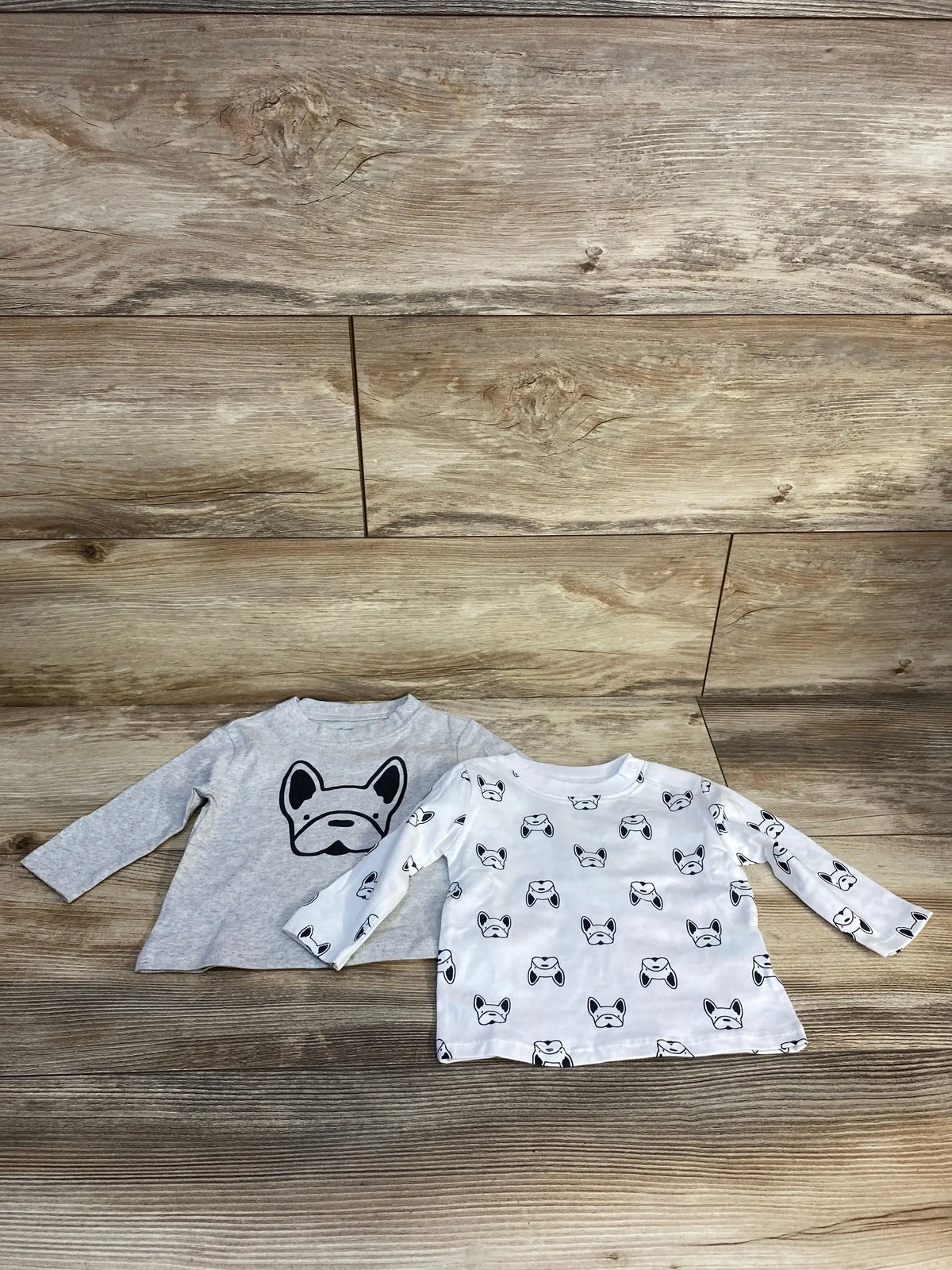 Two long sleeve toddler shirts with dog face prints on wooden background