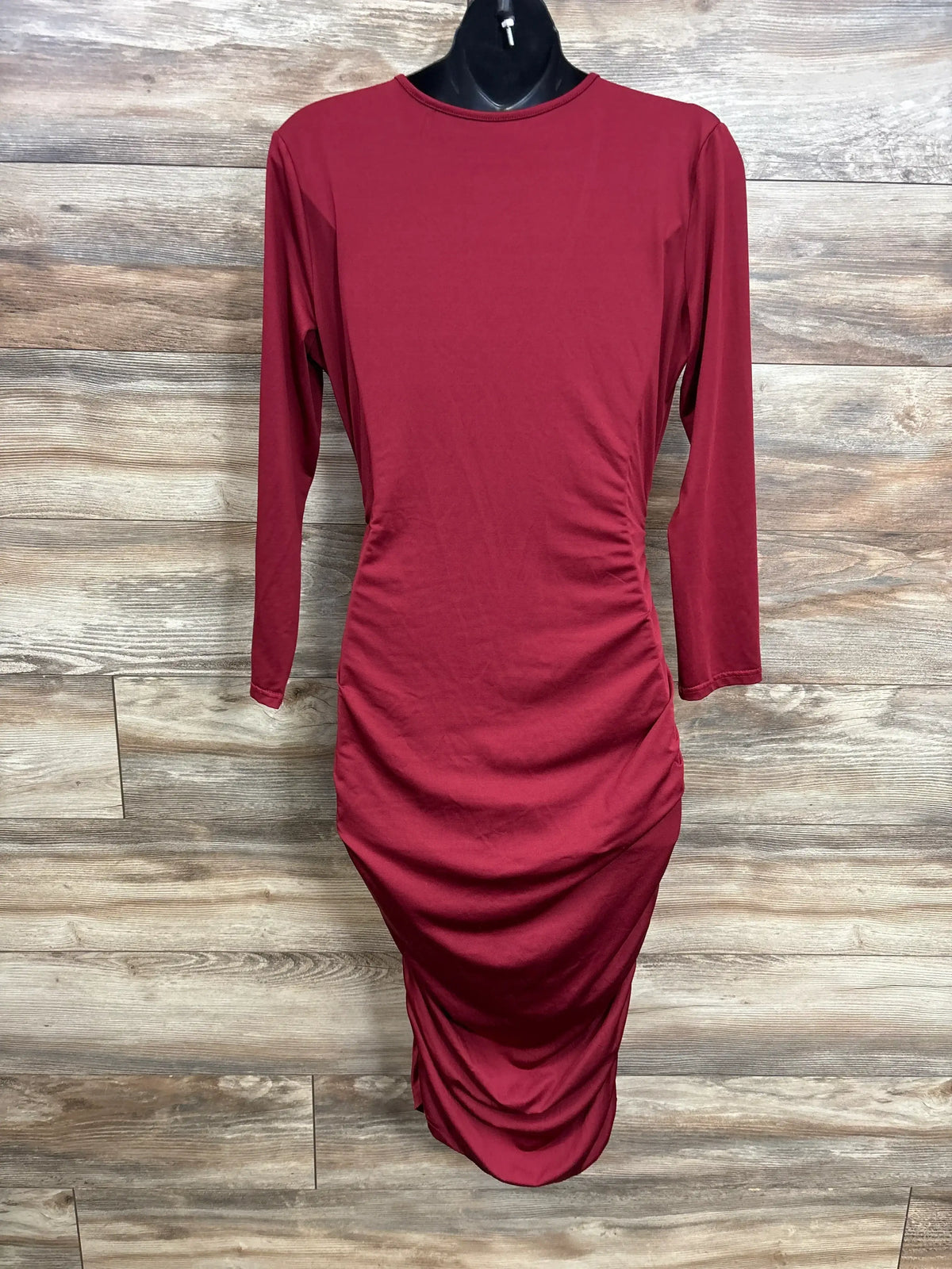 Wine red long sleeve midi dress with ruching, displayed on mannequin, wood background