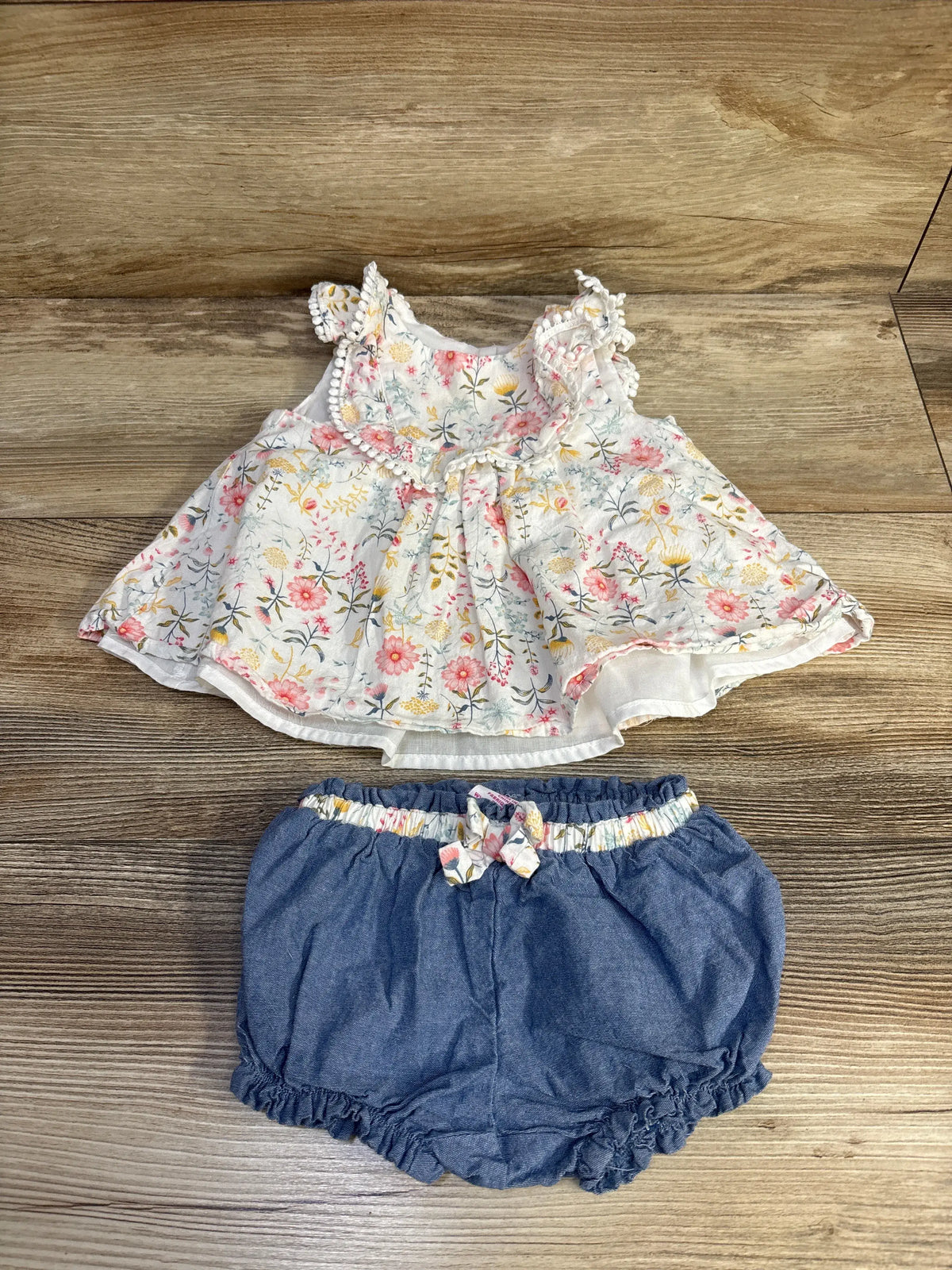 Flat lay of Tommy Bahama two-piece set showcasing floral sleeveless top and chambray shorts on a wooden background