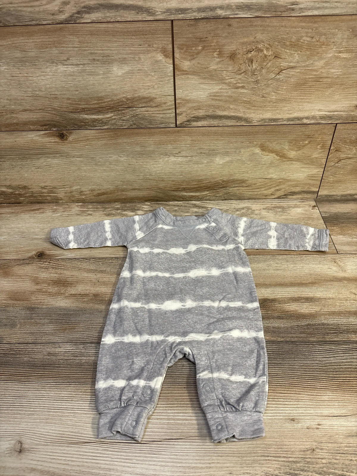 Front view of Geber grey striped coverall for 0 to 3 months with long sleeves and snap closures on a wood floor