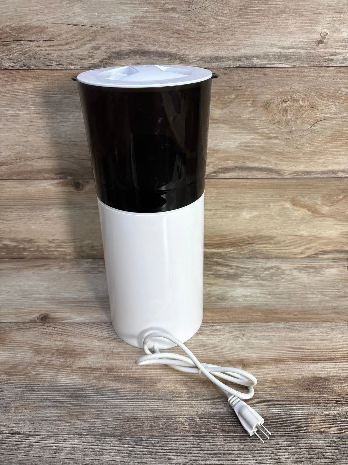Front view of Bellababy Instant Bottle Warmer showcasing its white cylindrical body and power cord on a wood surface