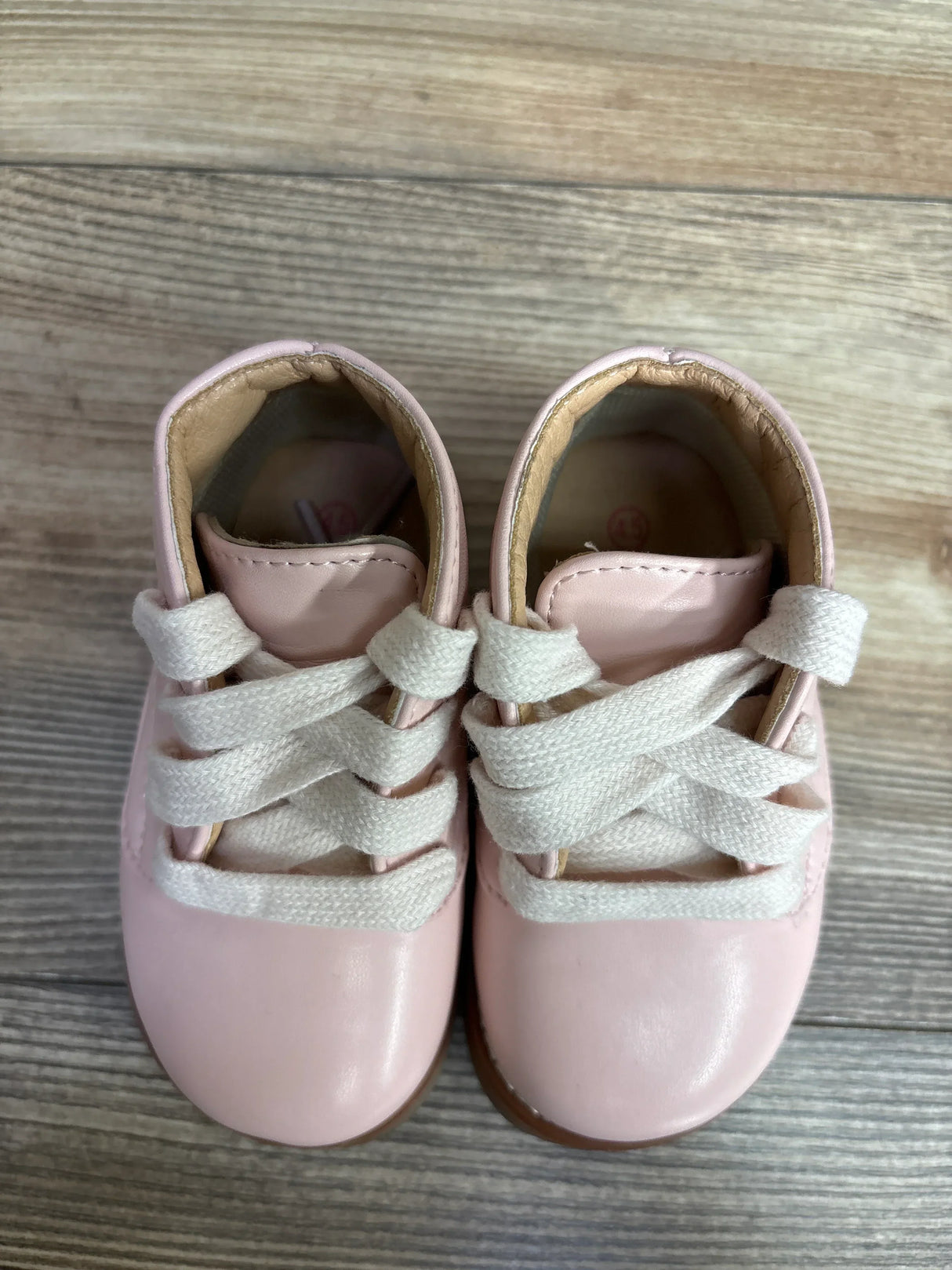 Top-down view of Josmo First Walker ankle shoes in pink showing white wide laces and padded collar on wooden floor