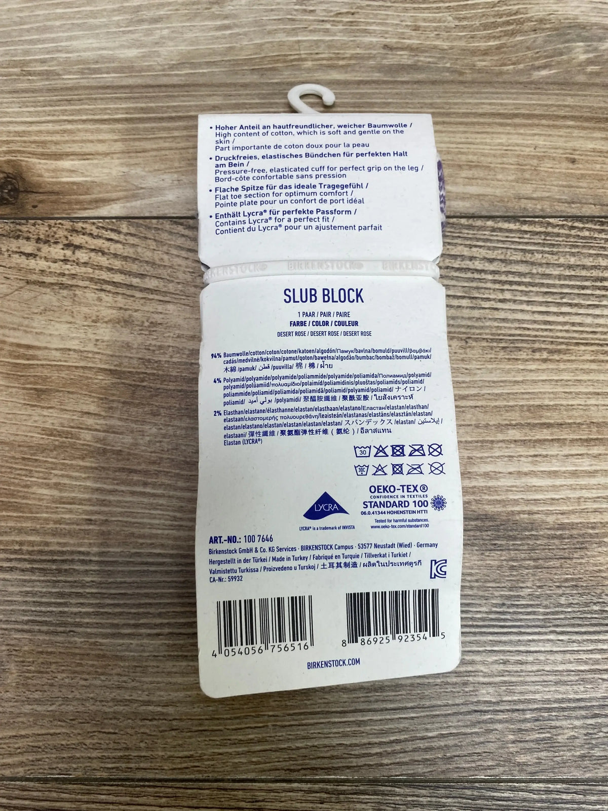 Back of NWT Birkenstock Socks Girls Desert Rose size 2Y showcasing Slub Block label with care details and barcode on wood plank floor