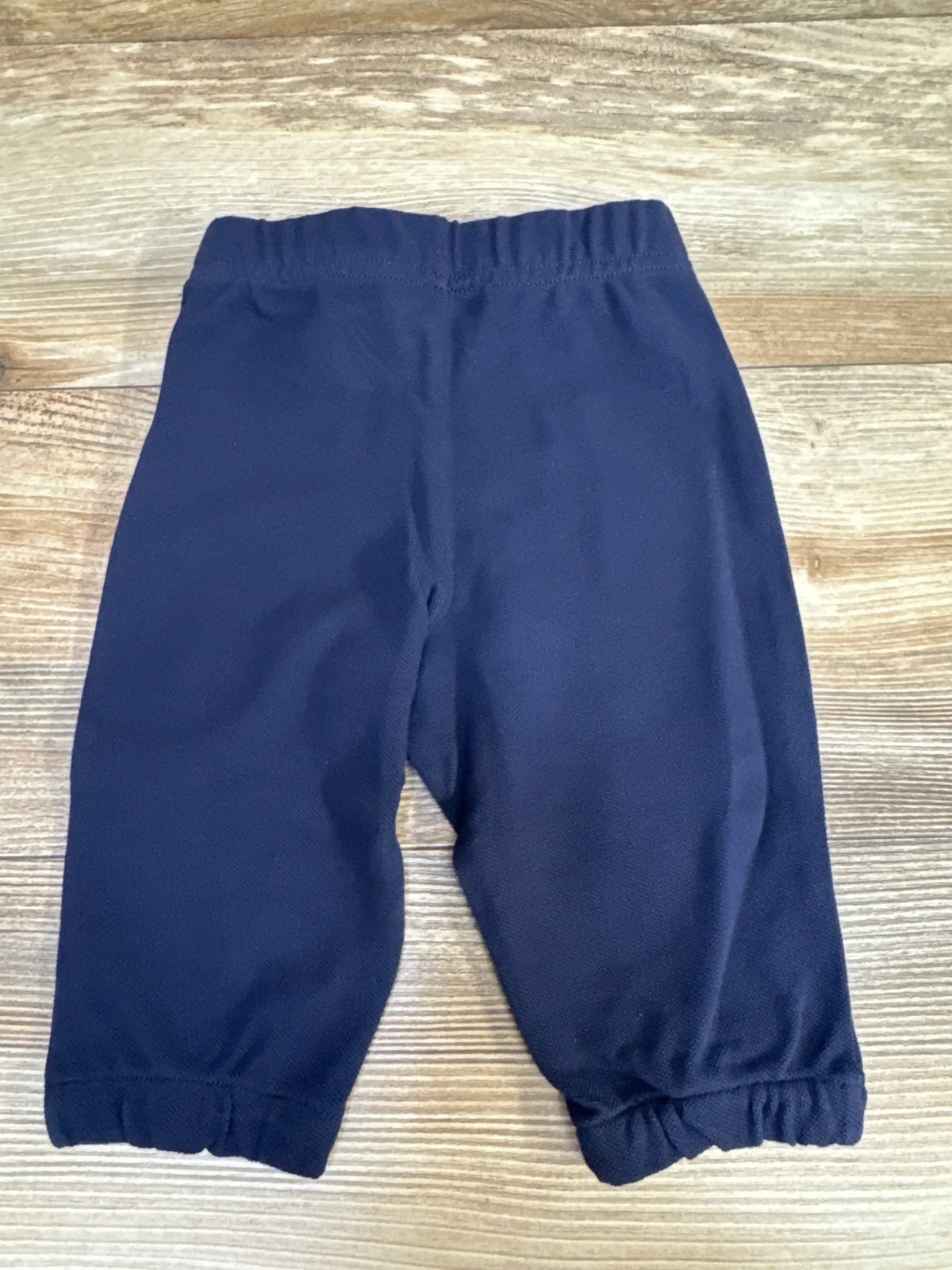 Top down view of navy Ralph Lauren baby sweatpants size 6 months showing elastic waistband and gathered ankle cuffs on light wood background