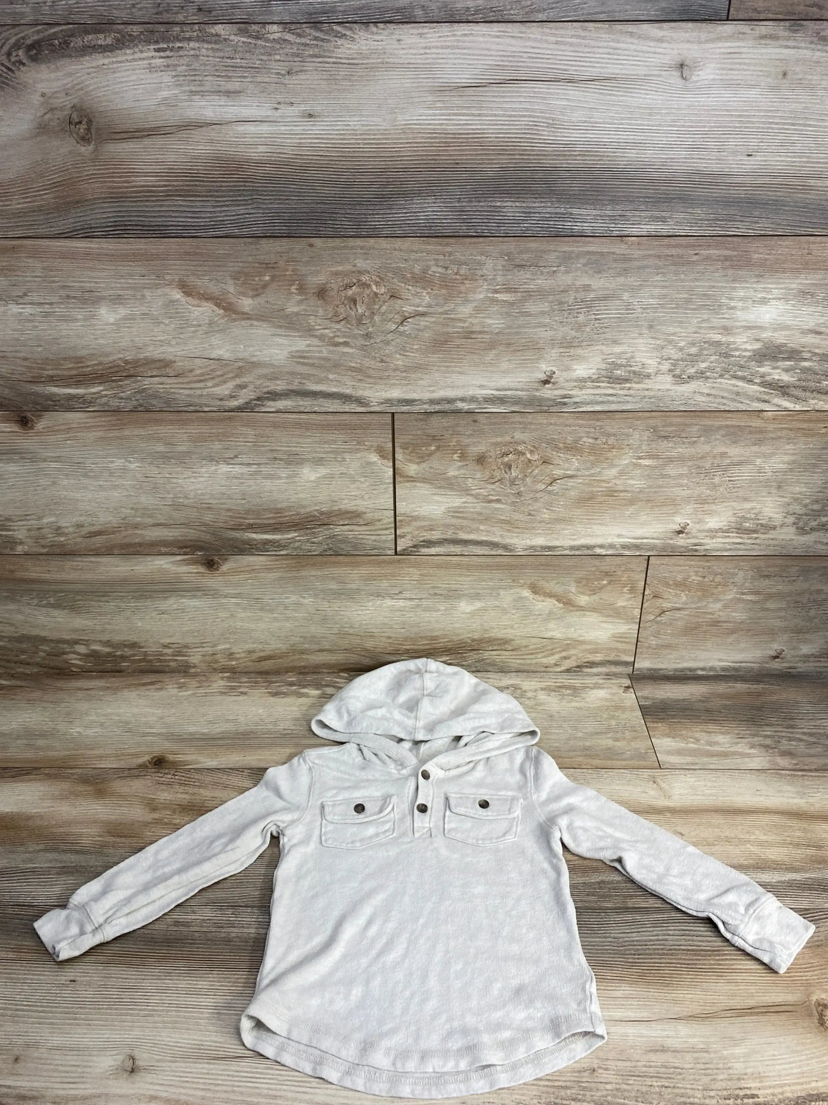 Light gray kids hooded long sleeve shirt with buttons and chest pockets on wood background