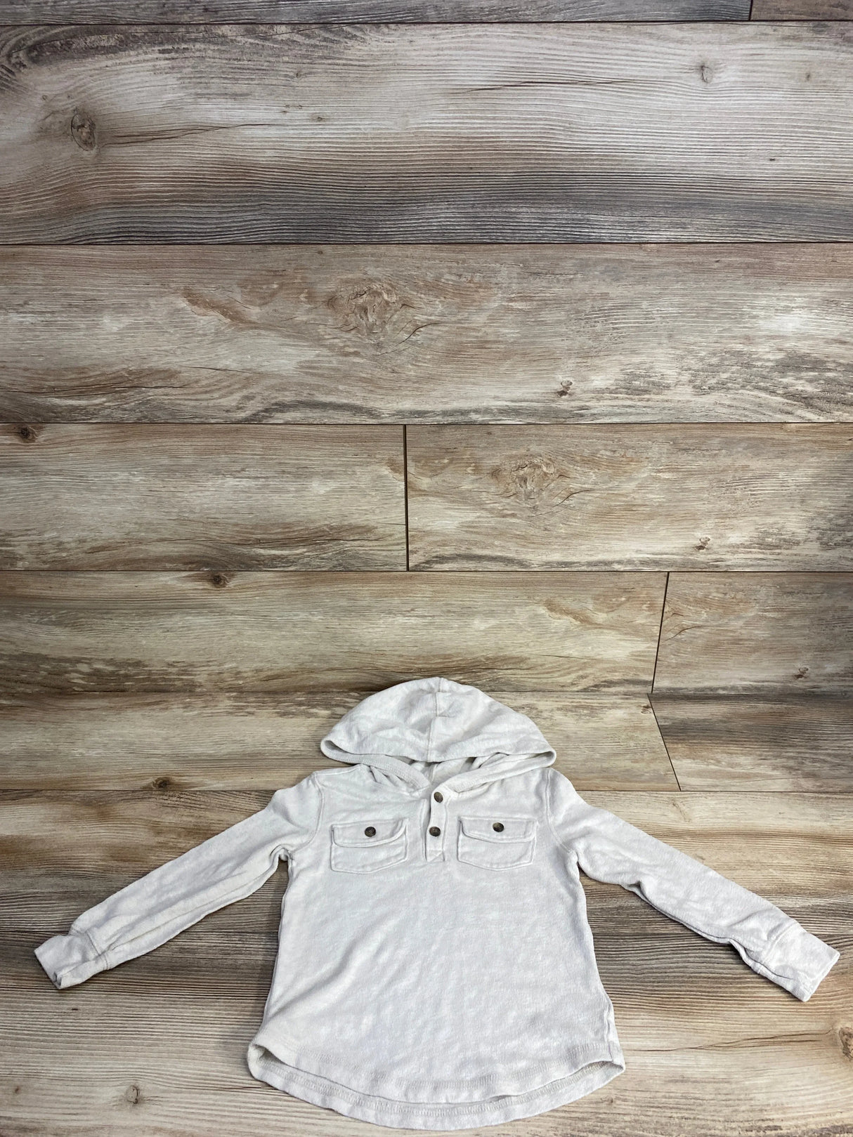 Light gray kids hooded long sleeve shirt with buttons and chest pockets on wood background