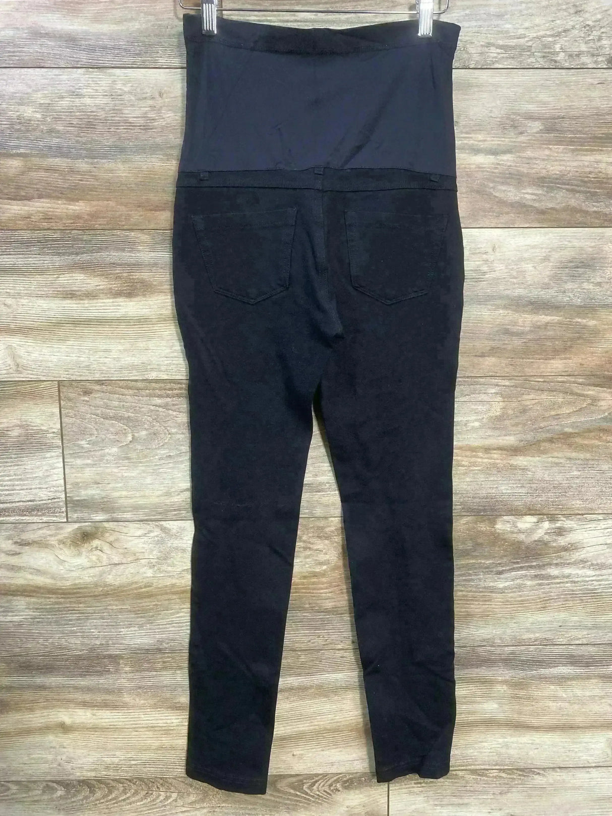 Back view of Pink Blush maternity full-panel black pants showcasing tall stretch belly panel and back pockets on wood floor background
