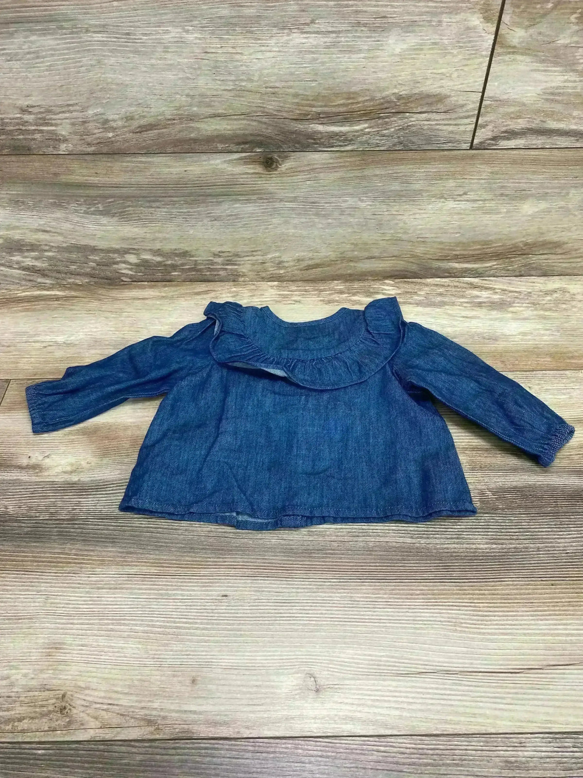 Front view of baby denim-look ruffle-trim long-sleeve top showcasing ruffle collar and elasticized cuffs on wood floor background