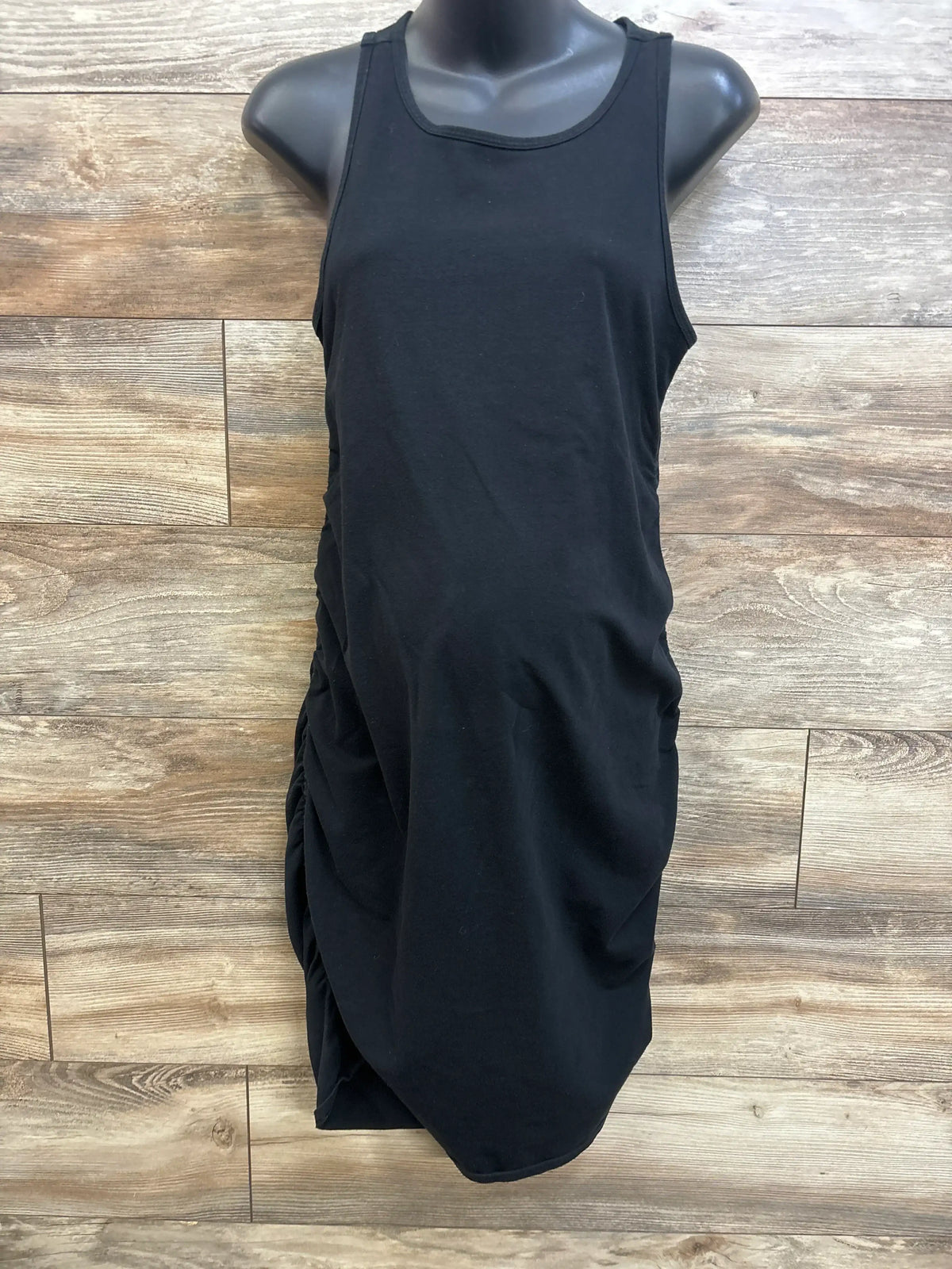 Front view of Isabel Maternity Tank Bodycon Dress size XL showcasing black sleeveless dress with ruched sides on mannequin and wood plank backdrop
