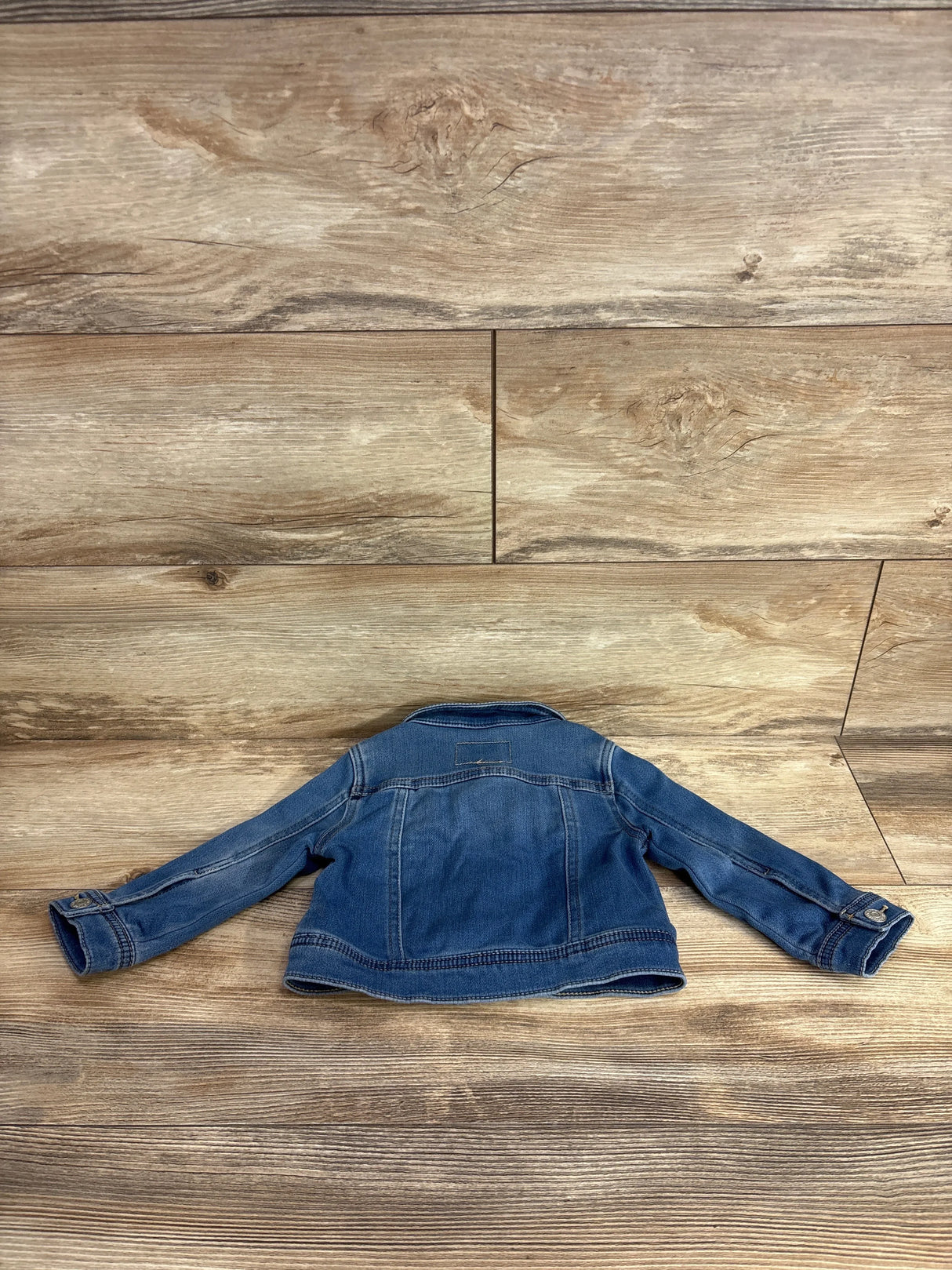 Children's denim jacket laid flat on wood floor, gently used kids clothing resale
