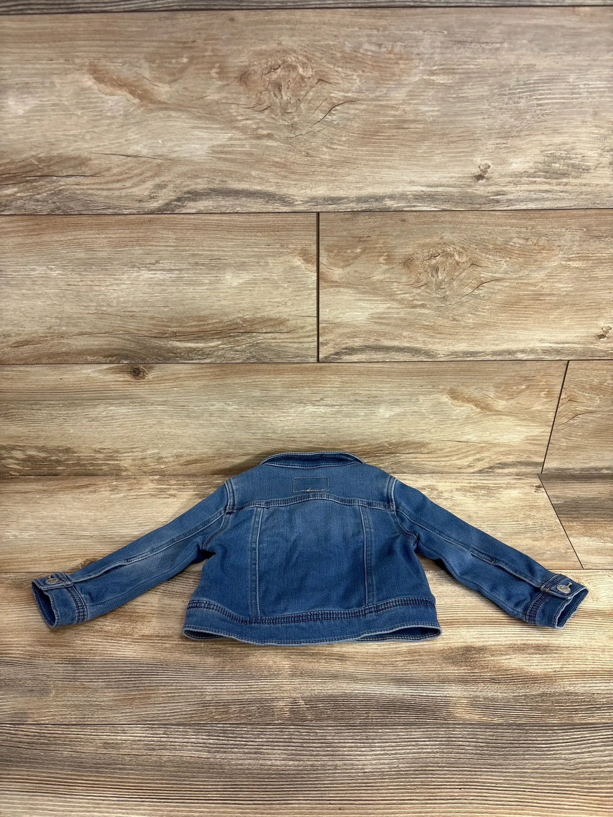 Children's denim jacket laid flat on wood floor, gently used kids clothing resale