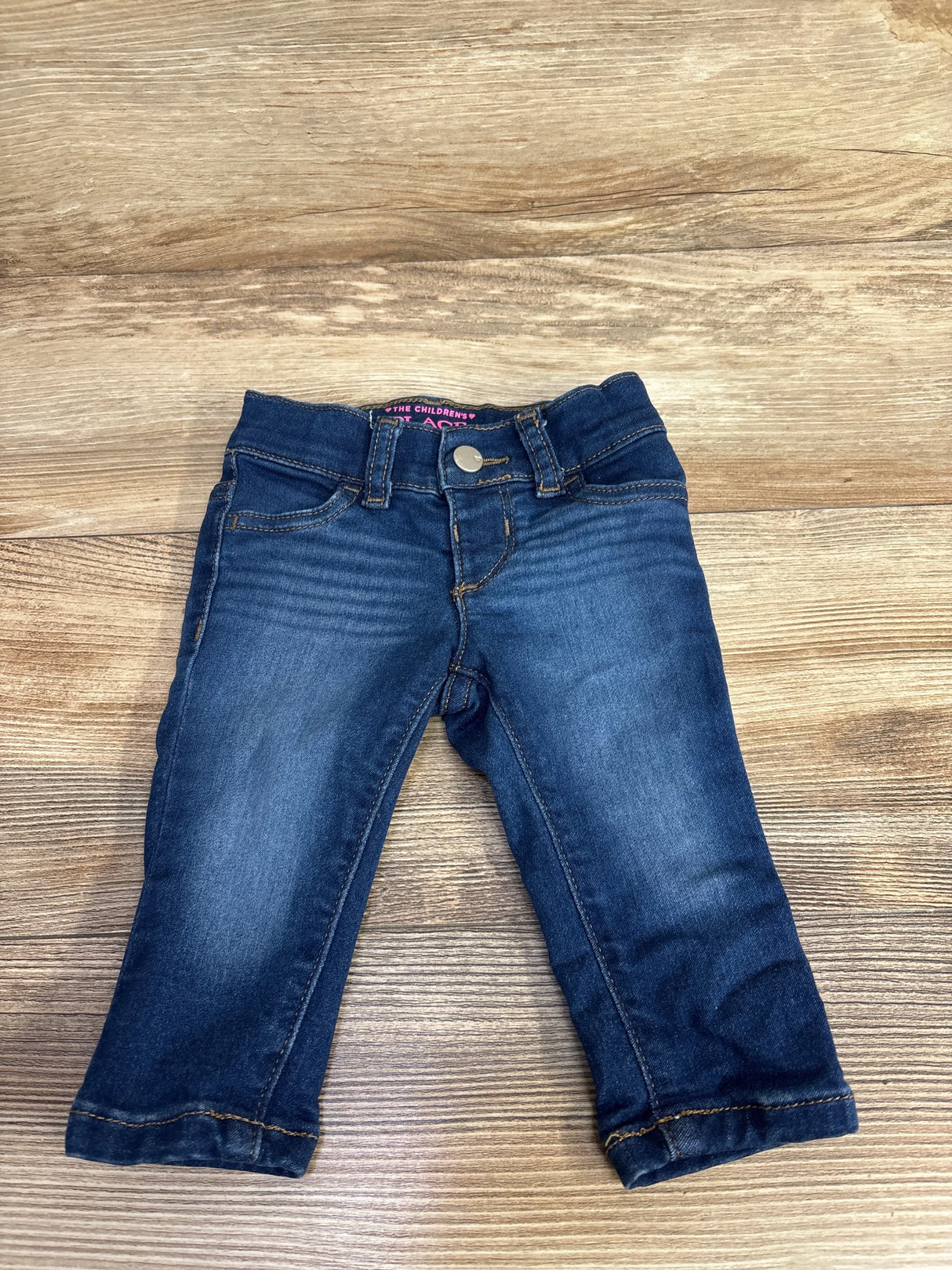 Toddler dark blue denim jeans with front pockets and button closure on wooden background