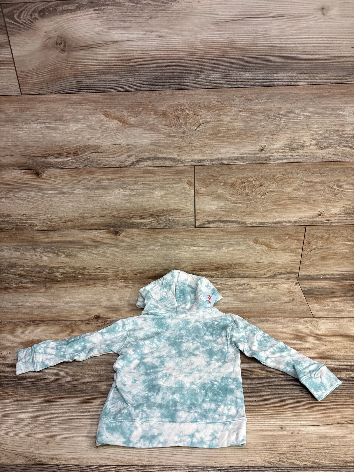 Kids tie-dye hoodie sweatshirt in green and white, laid flat on wooden background