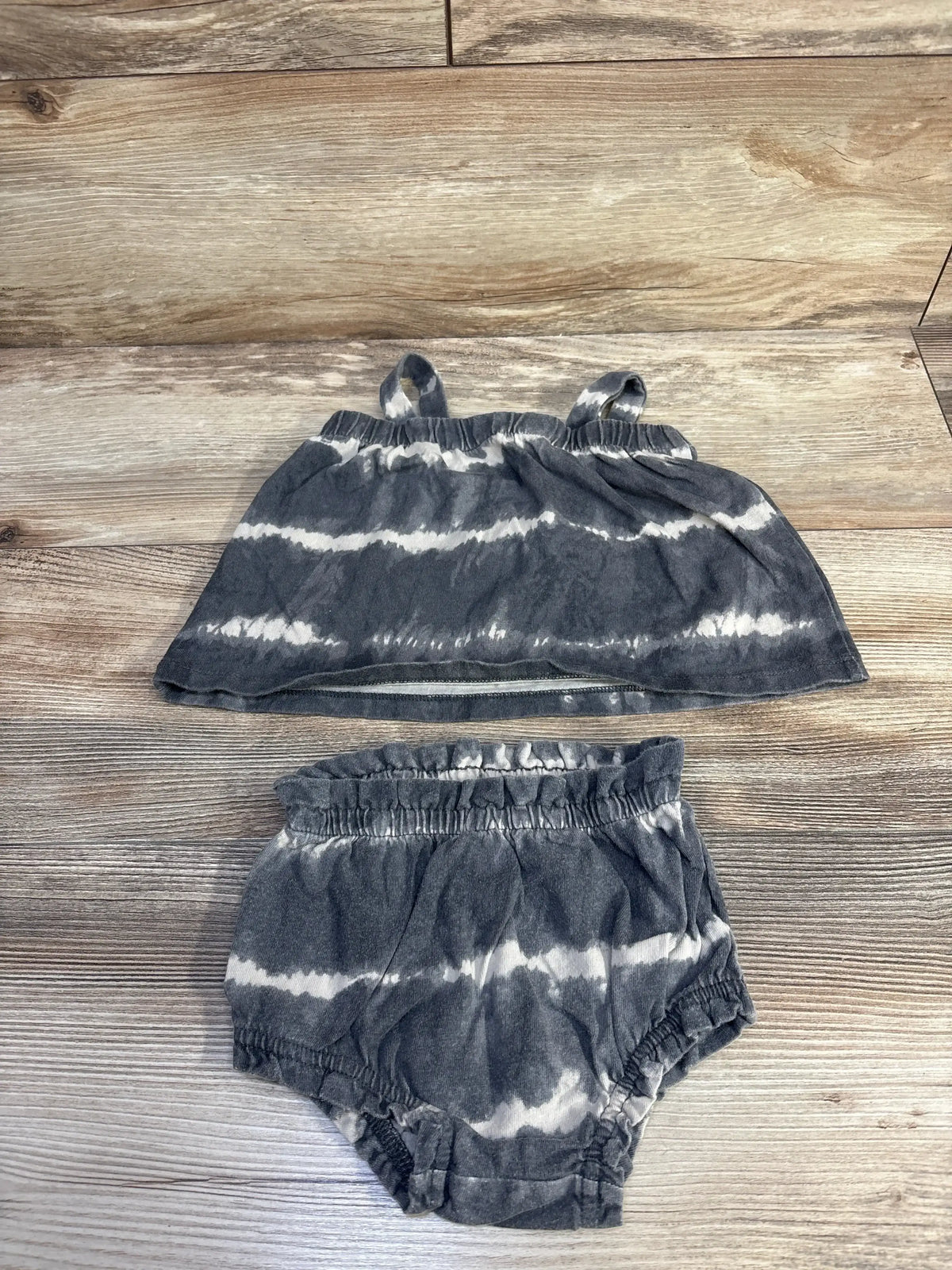 Top view of Baby Gap grey organic cotton tie-dye tank top and shorts set showcasing ruffled edges on wood