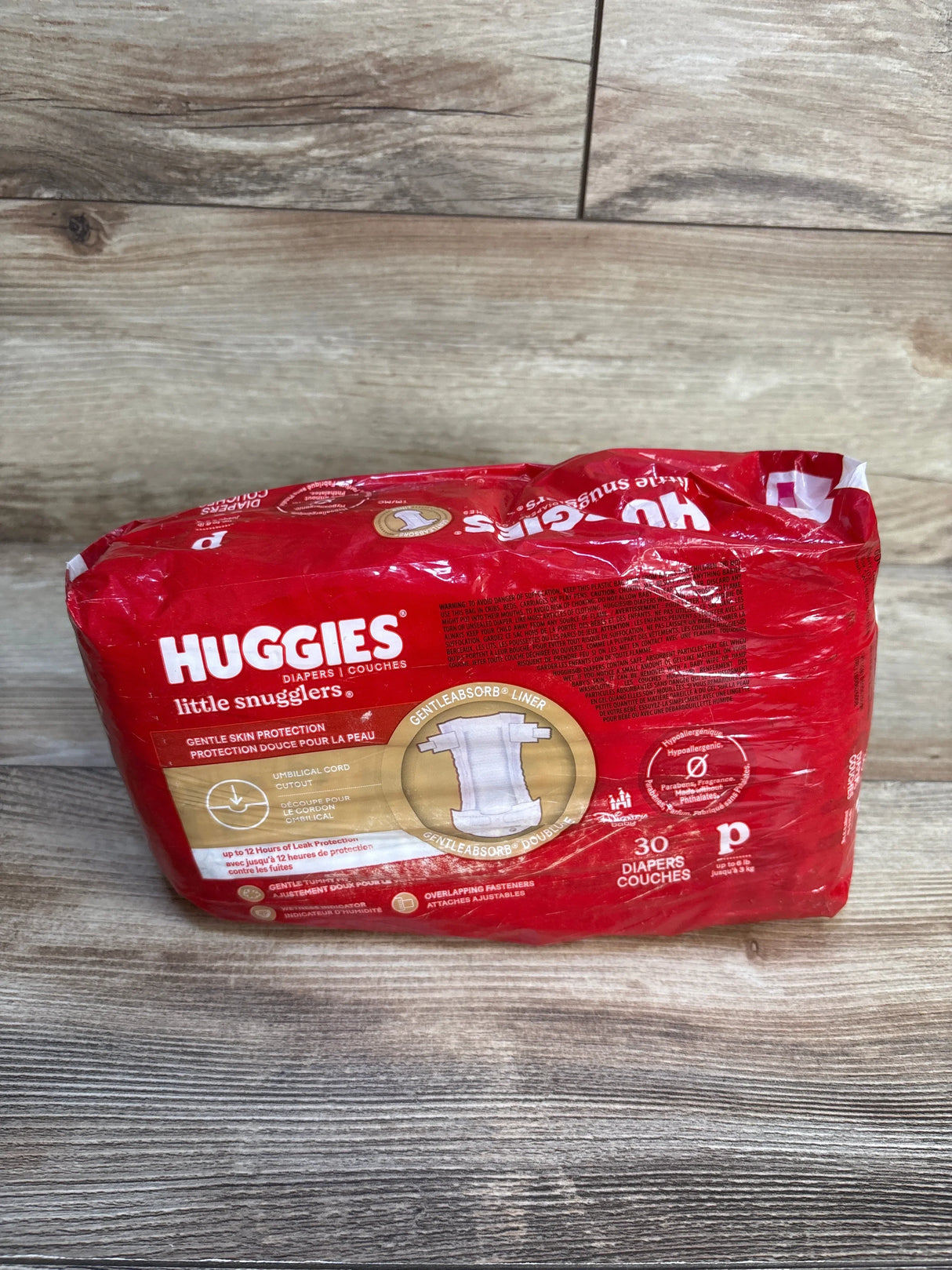 Front view of Huggies Little Snugglers preemie diaper pack showing gentle skin protection, 30 count, on wood floor