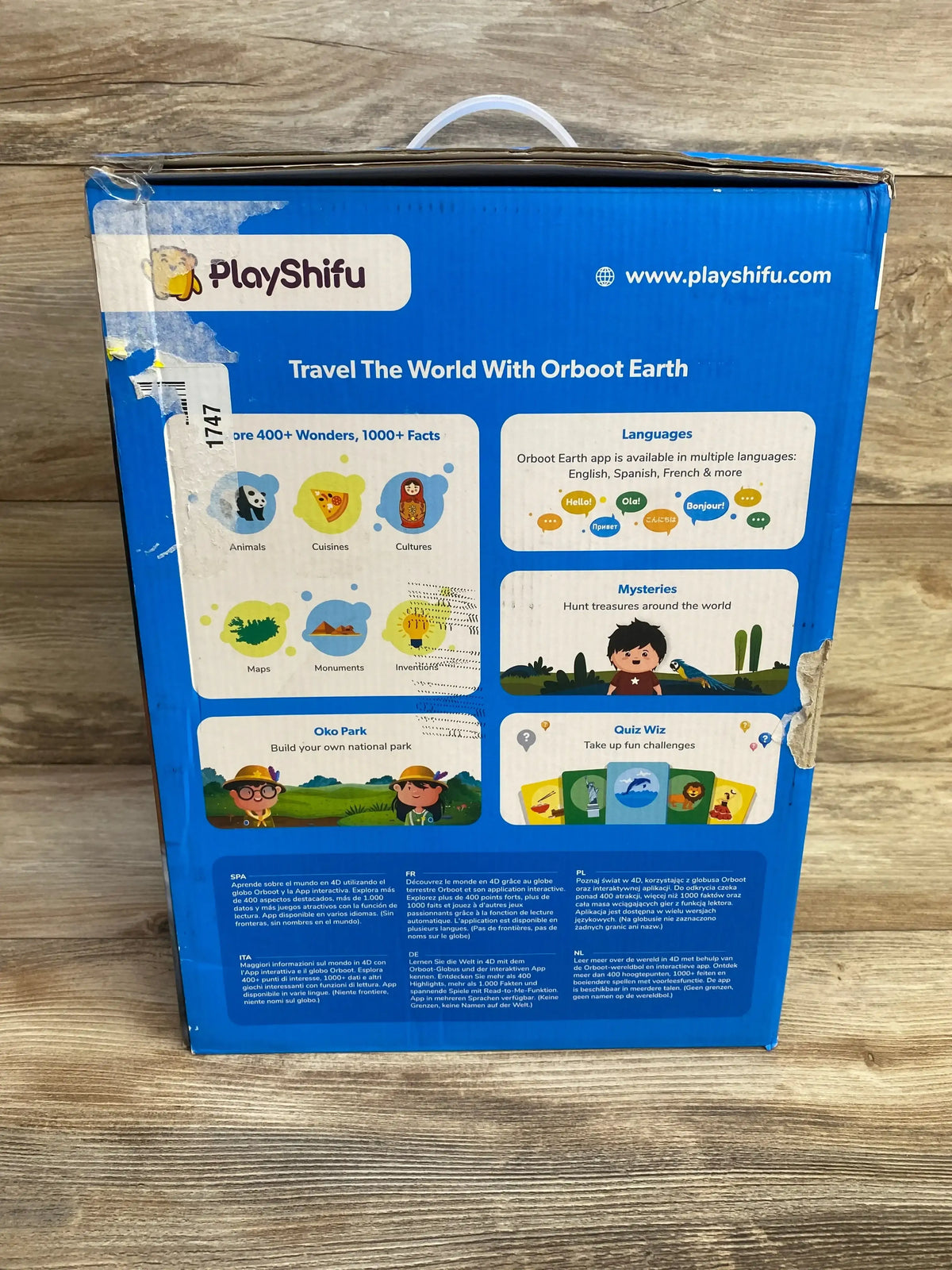 Rear view of PlayShifu Orboot Earth interactive AR globe box showing Travel The World With Orboot Earth headline and feature icons on blue packaging on a wooden floor