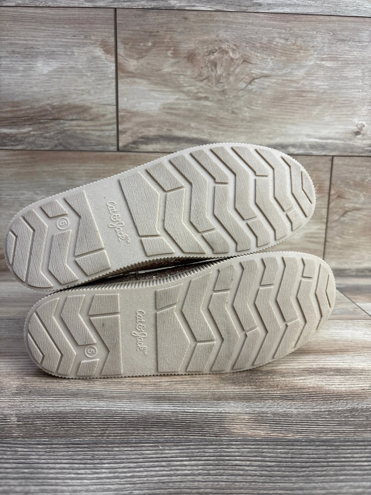 Pair of Cat & Jack kids shoe soles with zigzag tread on wood floor