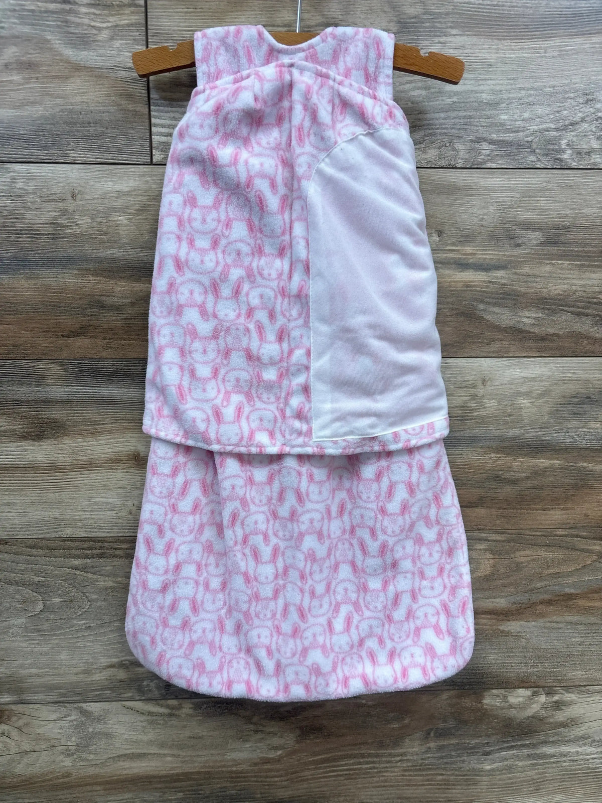 Pink and white baby sleep sack with bunny pattern, soft fleece, hanging on wooden hanger