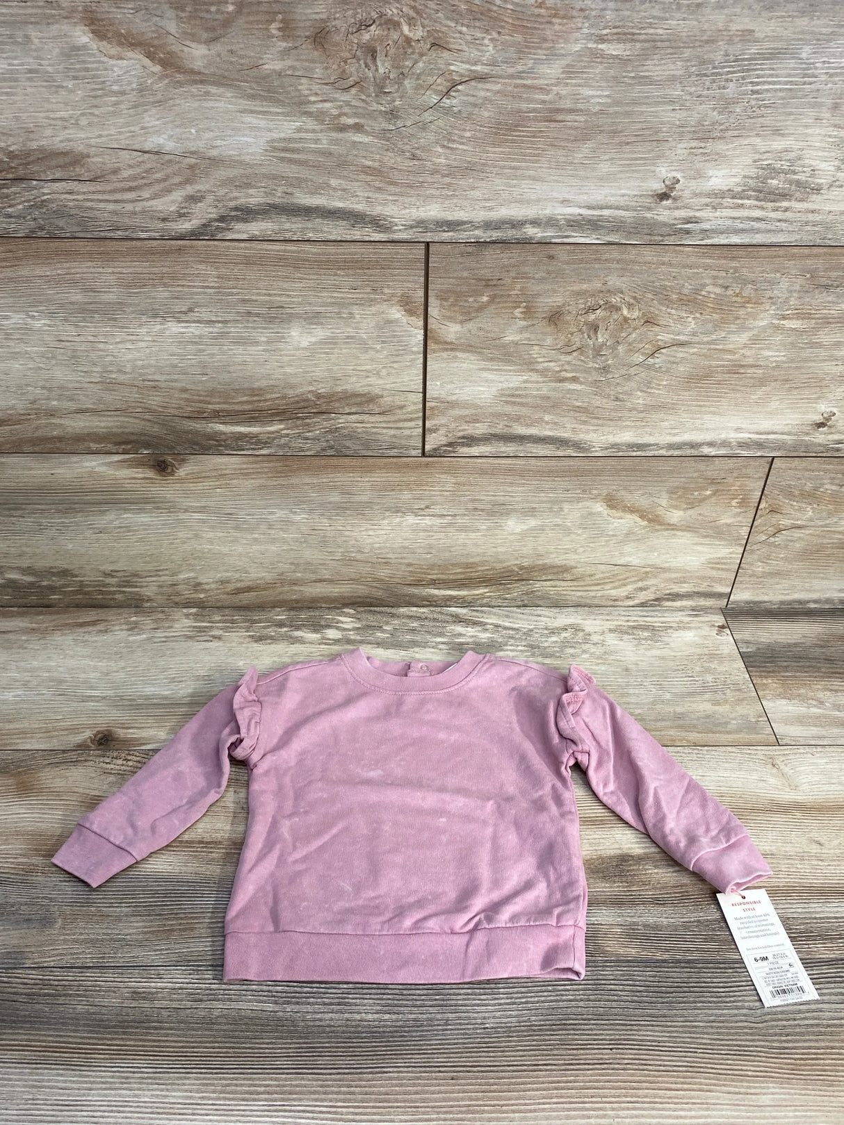 Light pink long sleeve toddler sweatshirt with ruffle details on wooden background