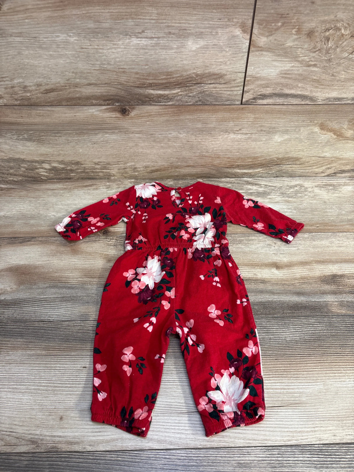 Red long-sleeve floral baby romper with white and pink flowers on wood floor