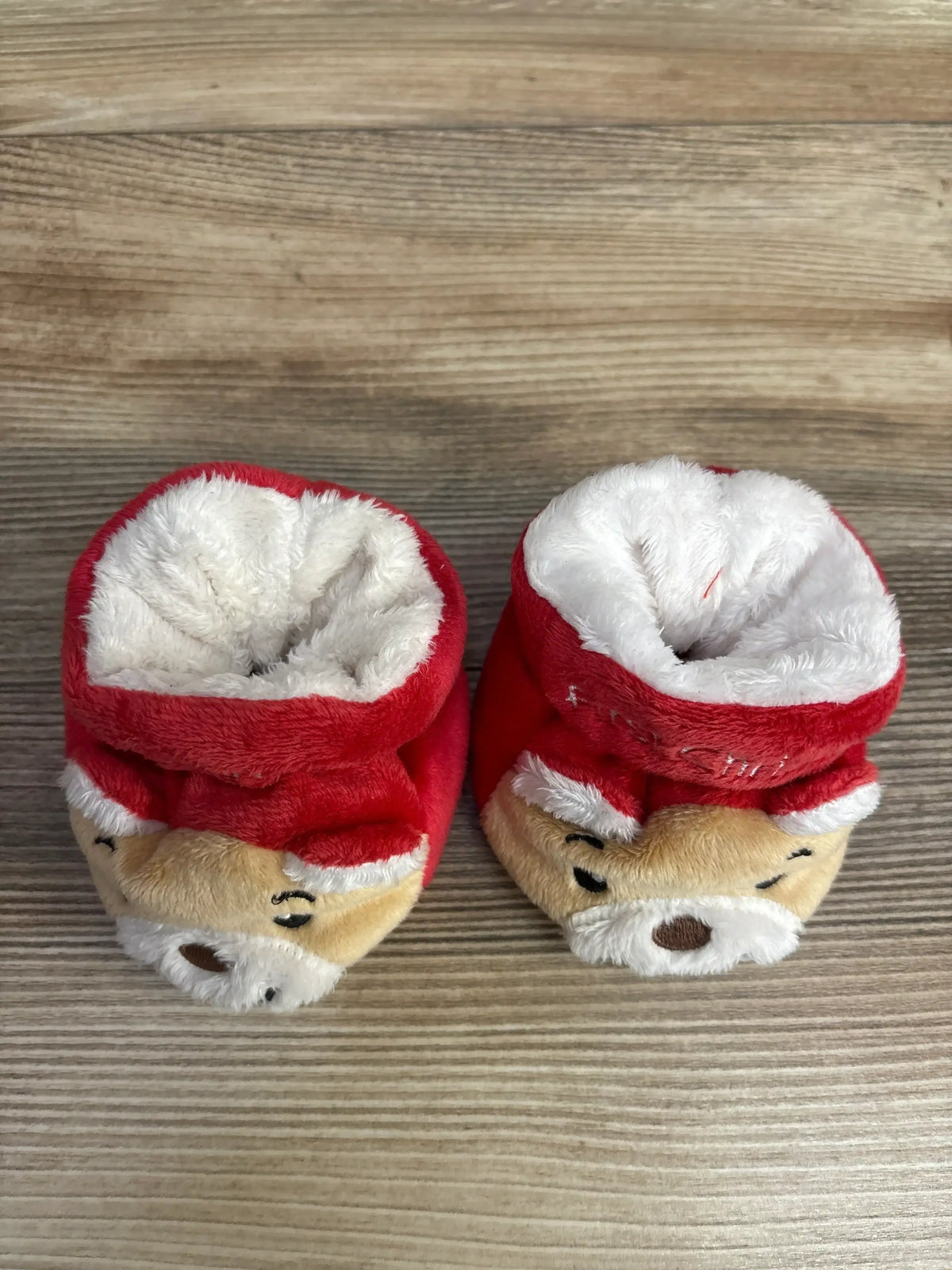 Adorable red and white plush baby booties with festive reindeer design, perfect for holiday outfits.