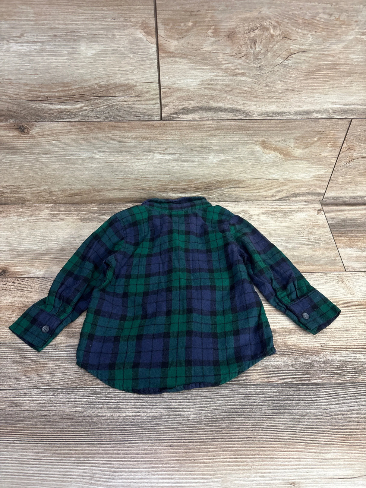 Back view of Old Navy toddler plaid flannel button-up shirt in green and navy showing long sleeves and button cuffs on wooden floor