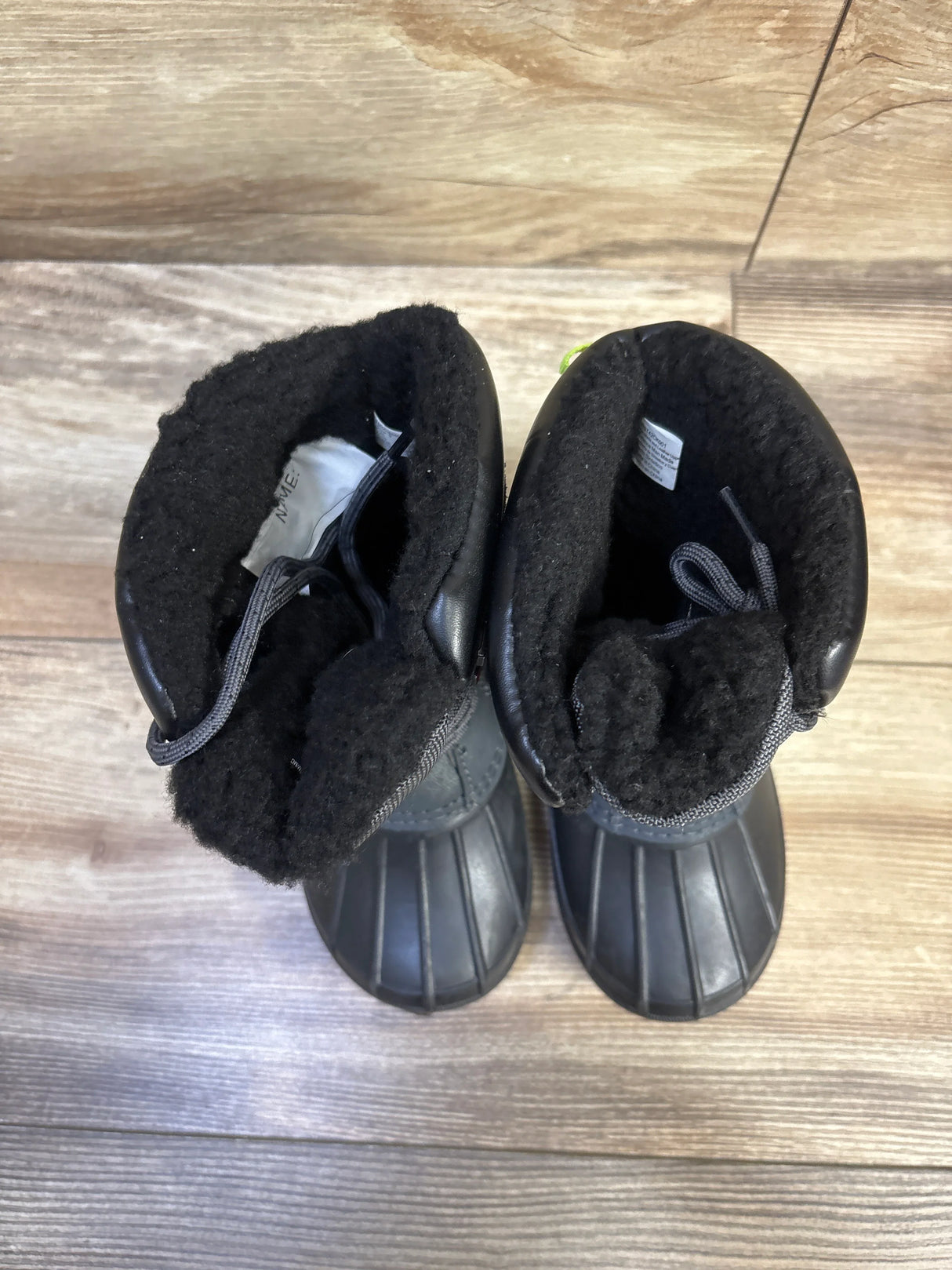 Top-down view of Swiss Tech black toddler winter boots (size 9C) showing plush black fleece lining and rubber lower on wood floor