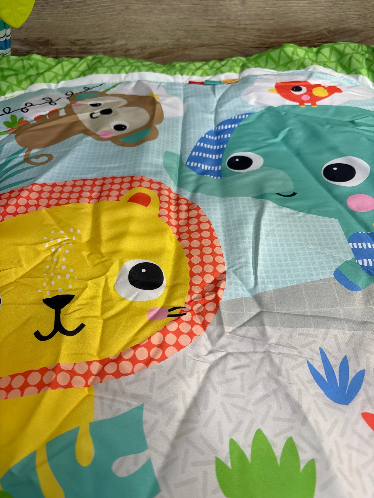Colorful baby play mat featuring cartoon lion, monkey, elephant, and bird with green border