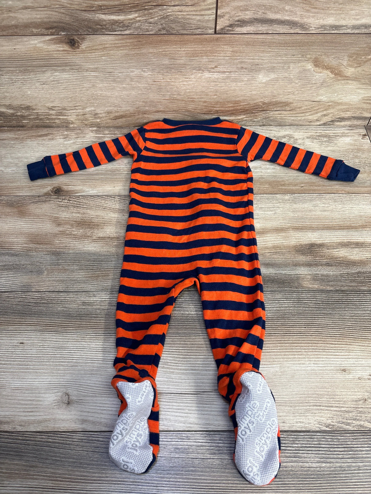Baby sleeper with orange and navy stripes and non-slip feet on wood background