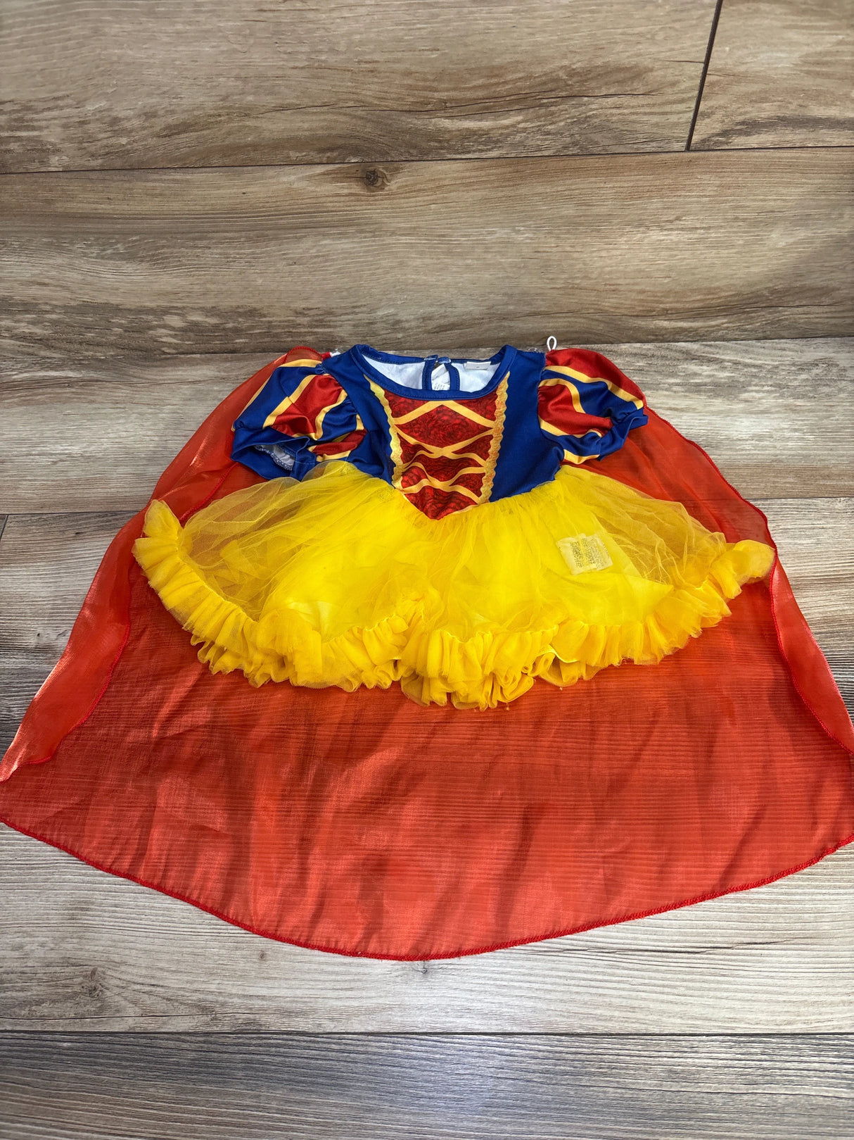 Snow White toddler costume dress with yellow tutu and red cape on wooden floor