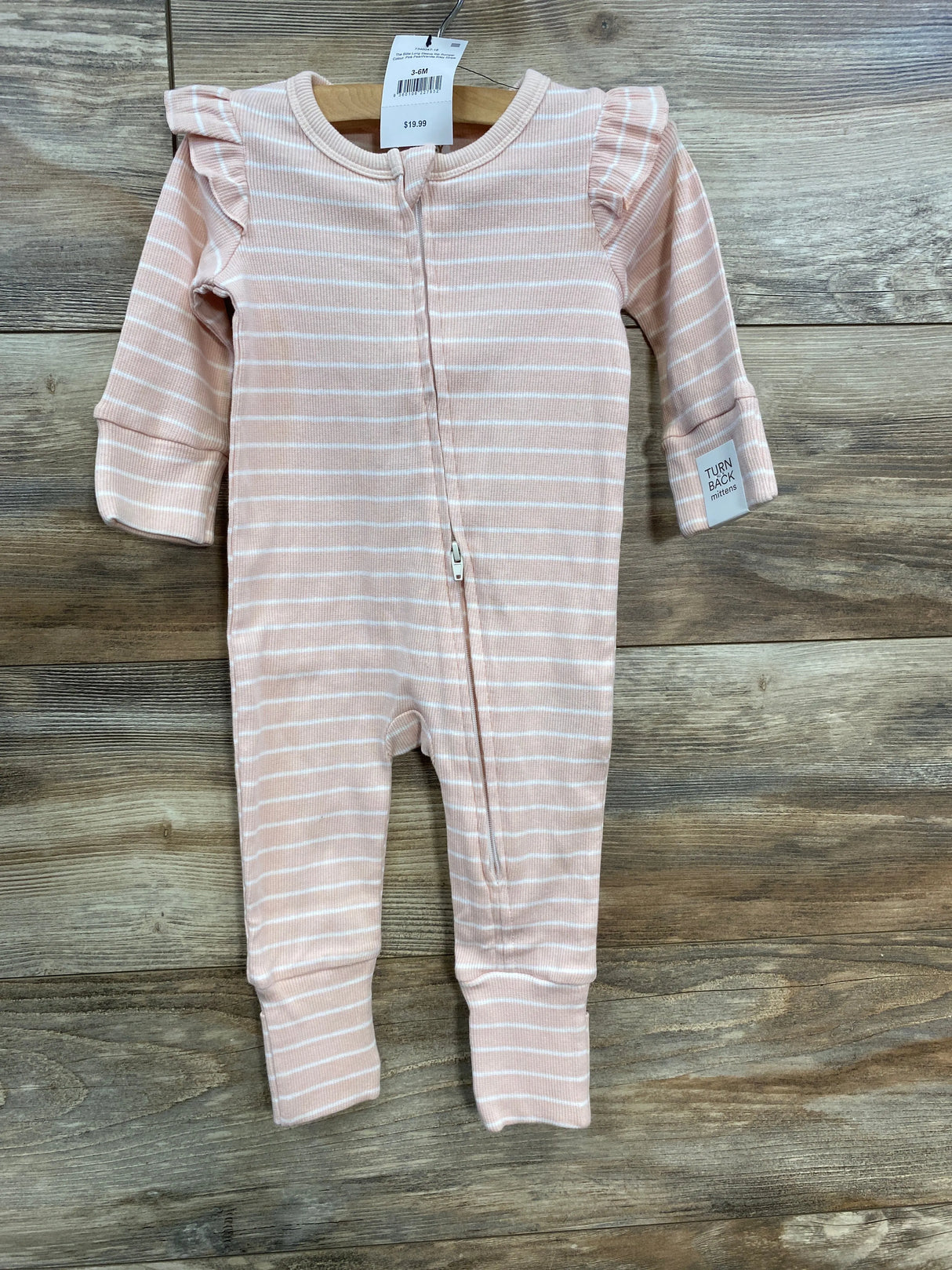 Pink and white striped baby romper with ruffle shoulders on wooden background