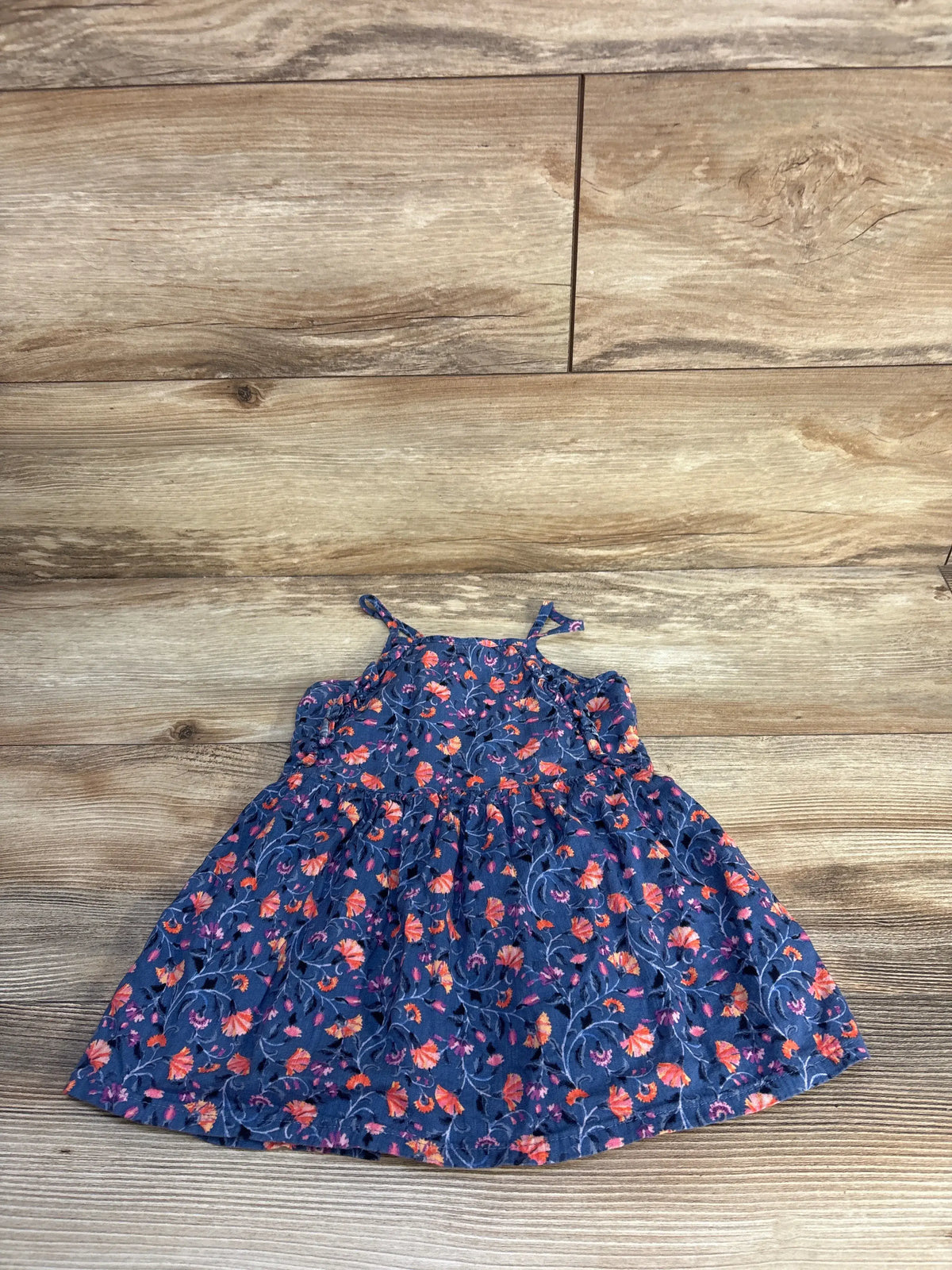Top-down view of Old Navy floral sleeveless dress showcasing ruffle-trimmed bodice and flared skirt on wood flooring