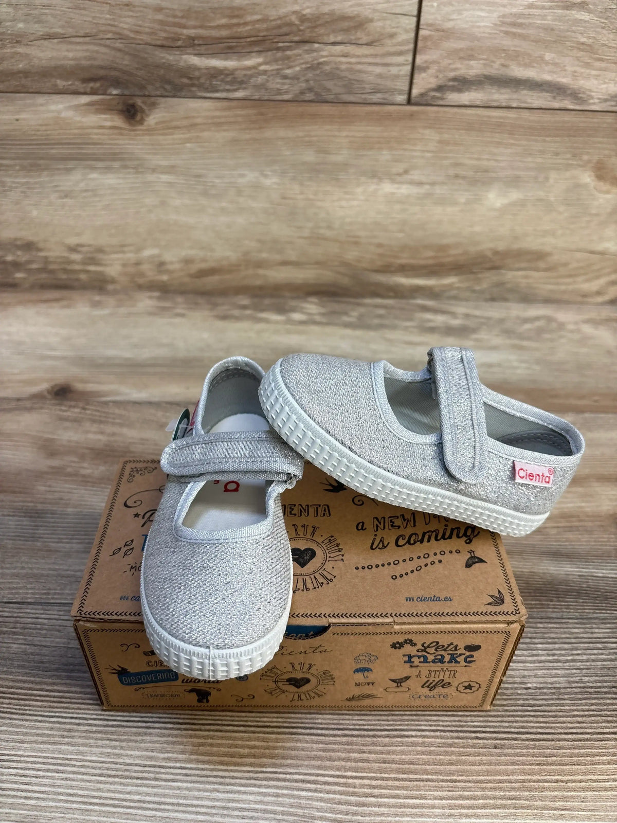 Silver glitter toddler Mary Jane shoes with Velcro strap on a decorative box, wood background