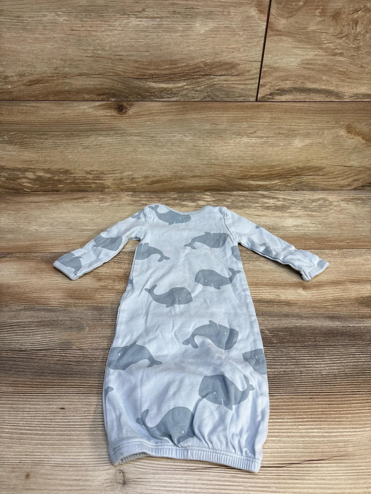 Light blue baby sleep gown with gray whale print, laid flat on wooden background