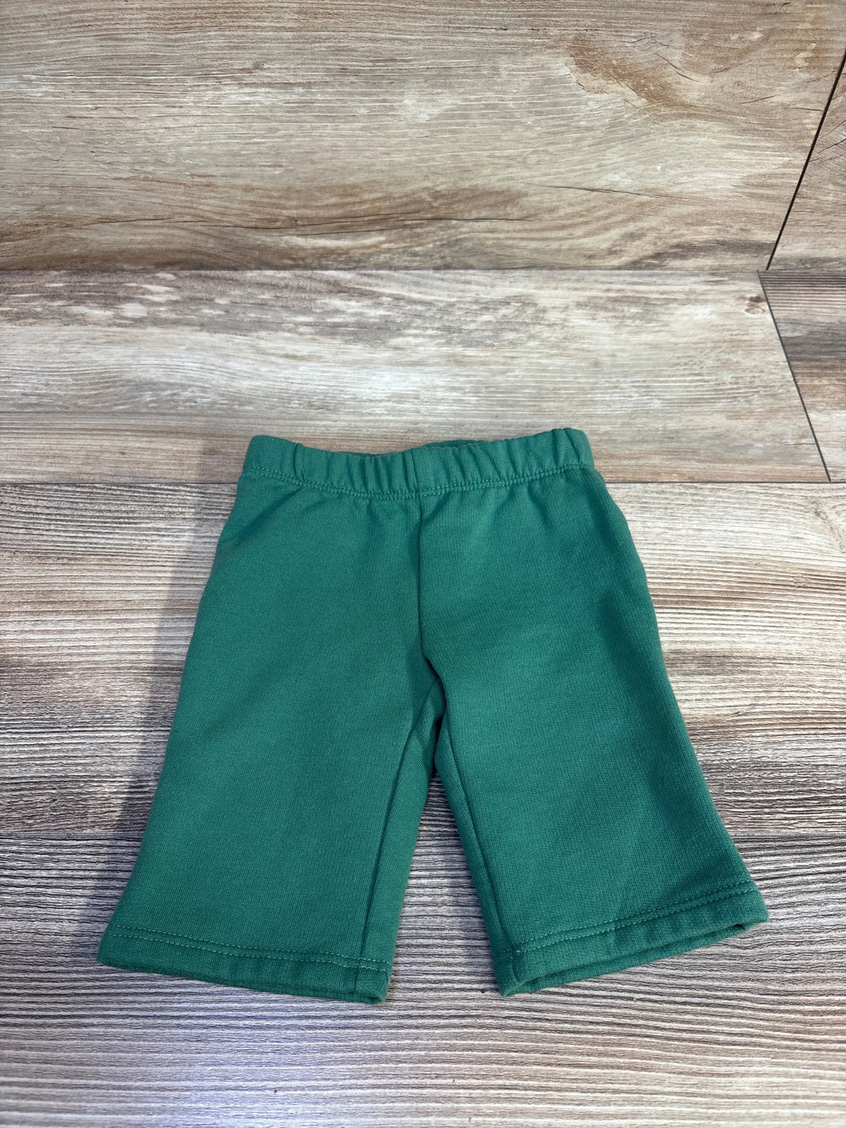 Front view of Cat & Jack green pull-on joggers showcasing elastic waistband and relaxed fit with wood-patterned background